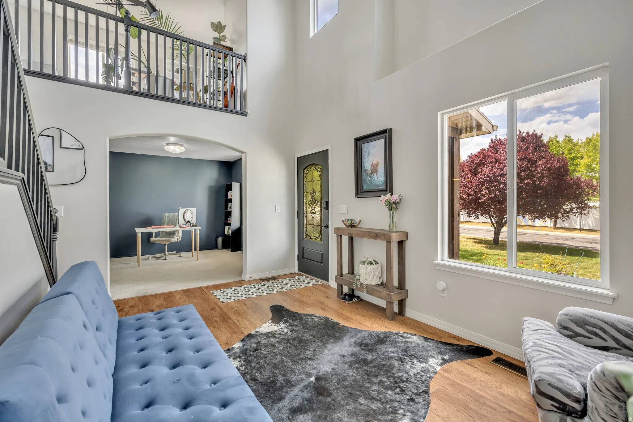 Living area featuring arched walkways, light wood-style floors, and a high ceiling
