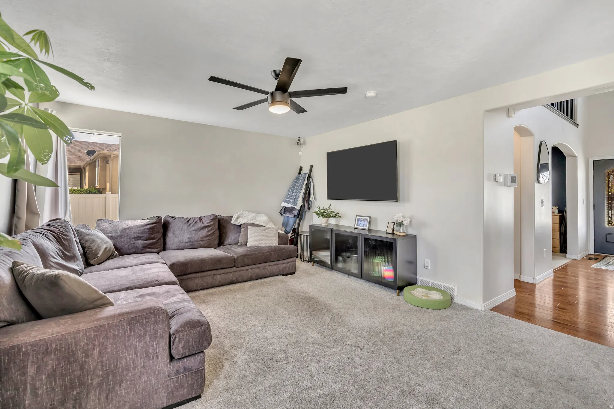 Living room with arched walkways, carpet floors, and ceiling fan
