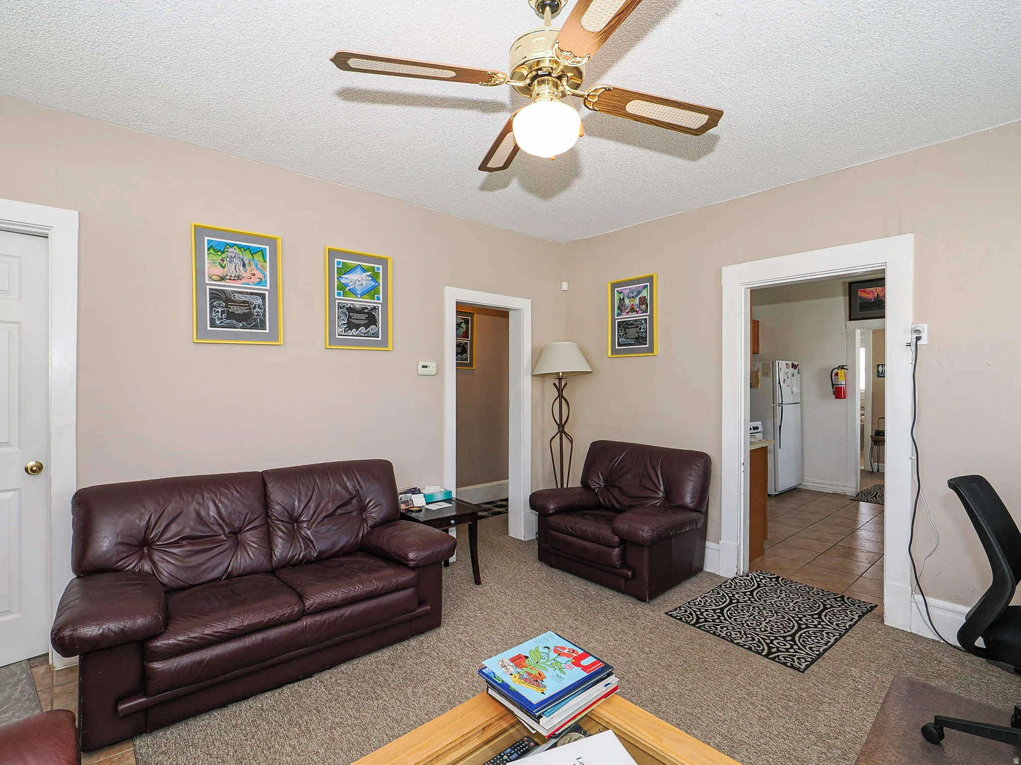 Living room featuring a textured ceiling, light colored carpet, and a ceiling fan