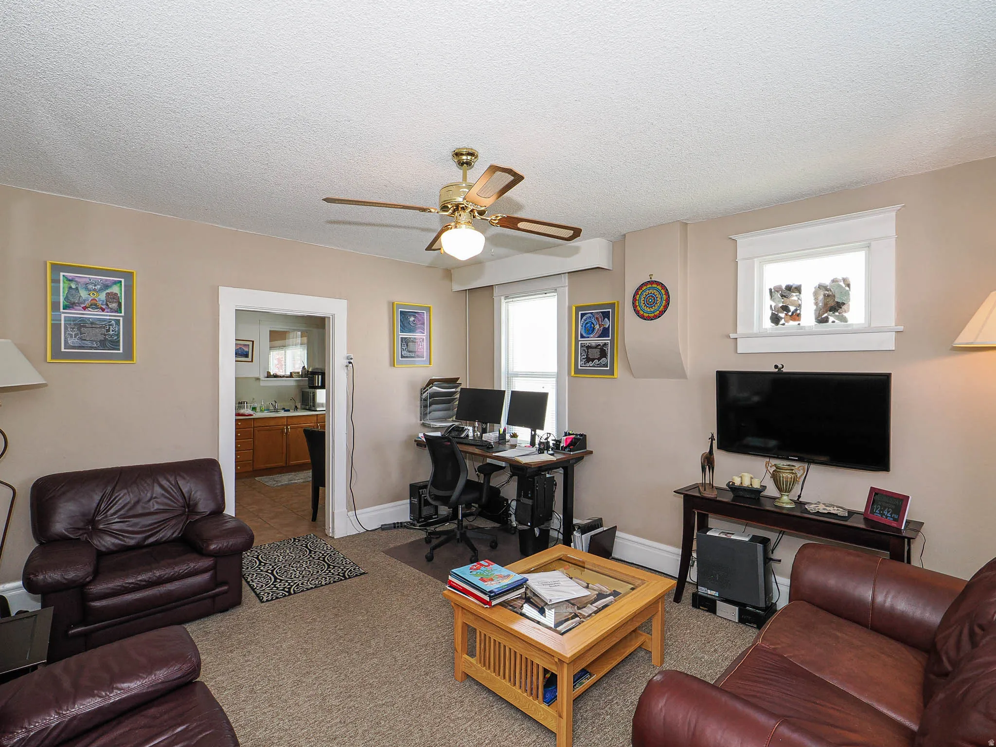 Carpeted living area with a desk, a textured ceiling, and a ceiling fan