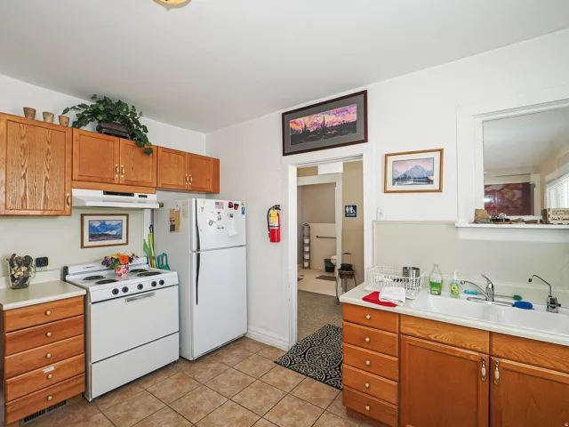 Kitchen featuring wood finish cabinetry, white appliances, light countertops, and light tile patterned flooring