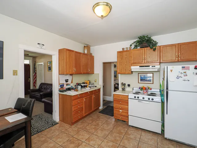 Kitchen with white appliances, light countertops, wood finish cabinets, and light tile patterned floors