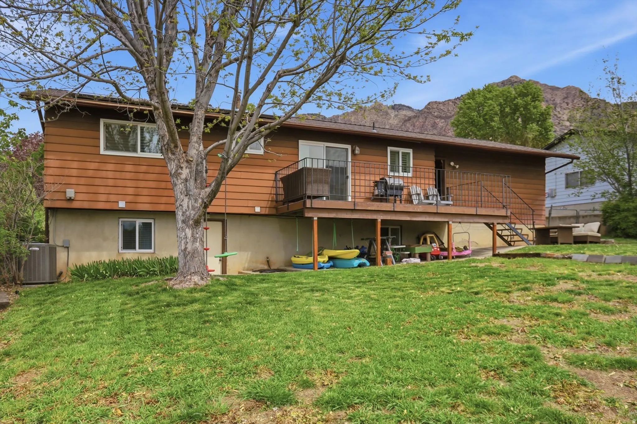 Rear view of property with a lawn and a deck with mountain view