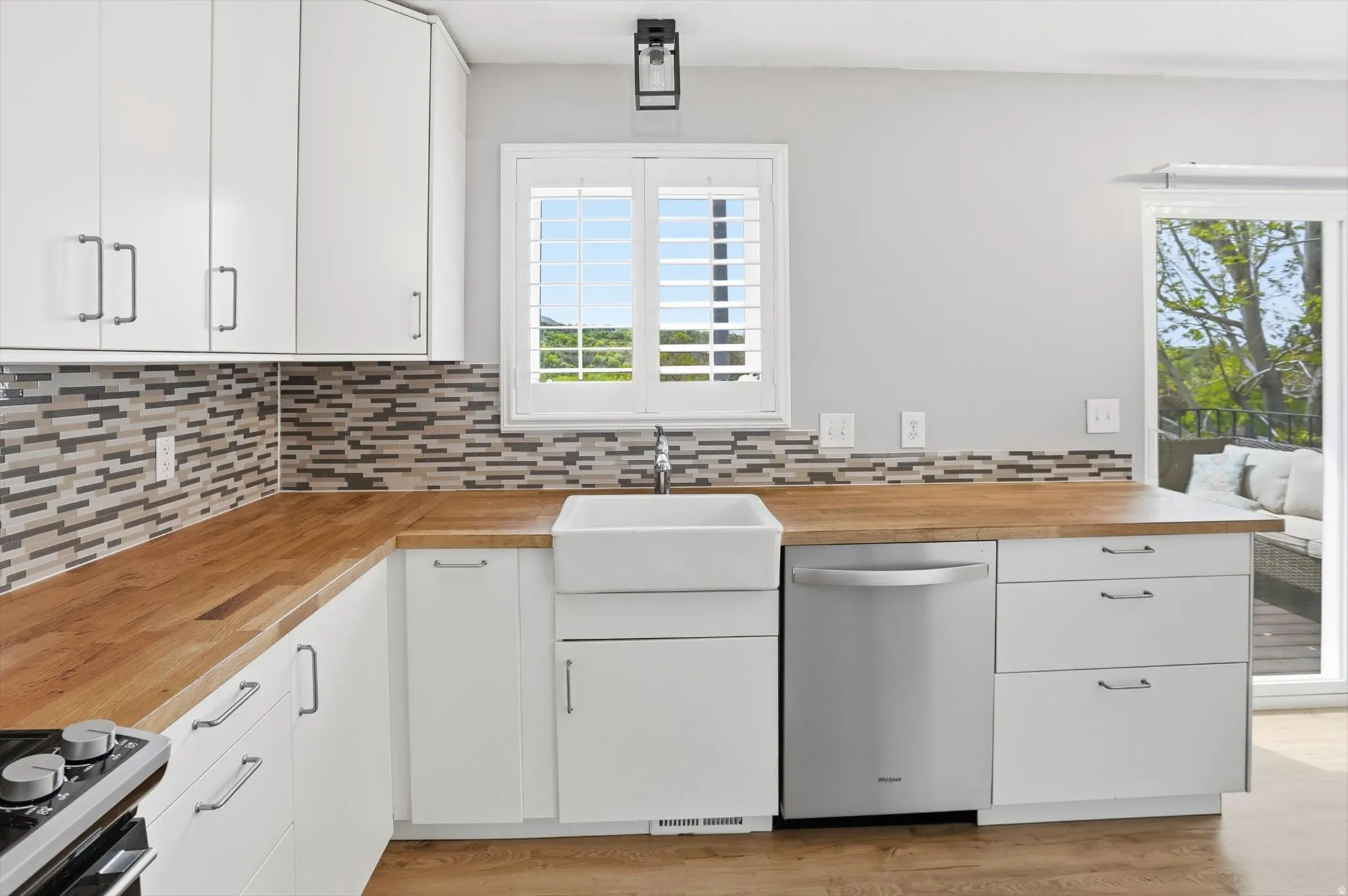 Kitchen featuring white cabinets, butcher block countertops, dishwasher, and light wood finished floors