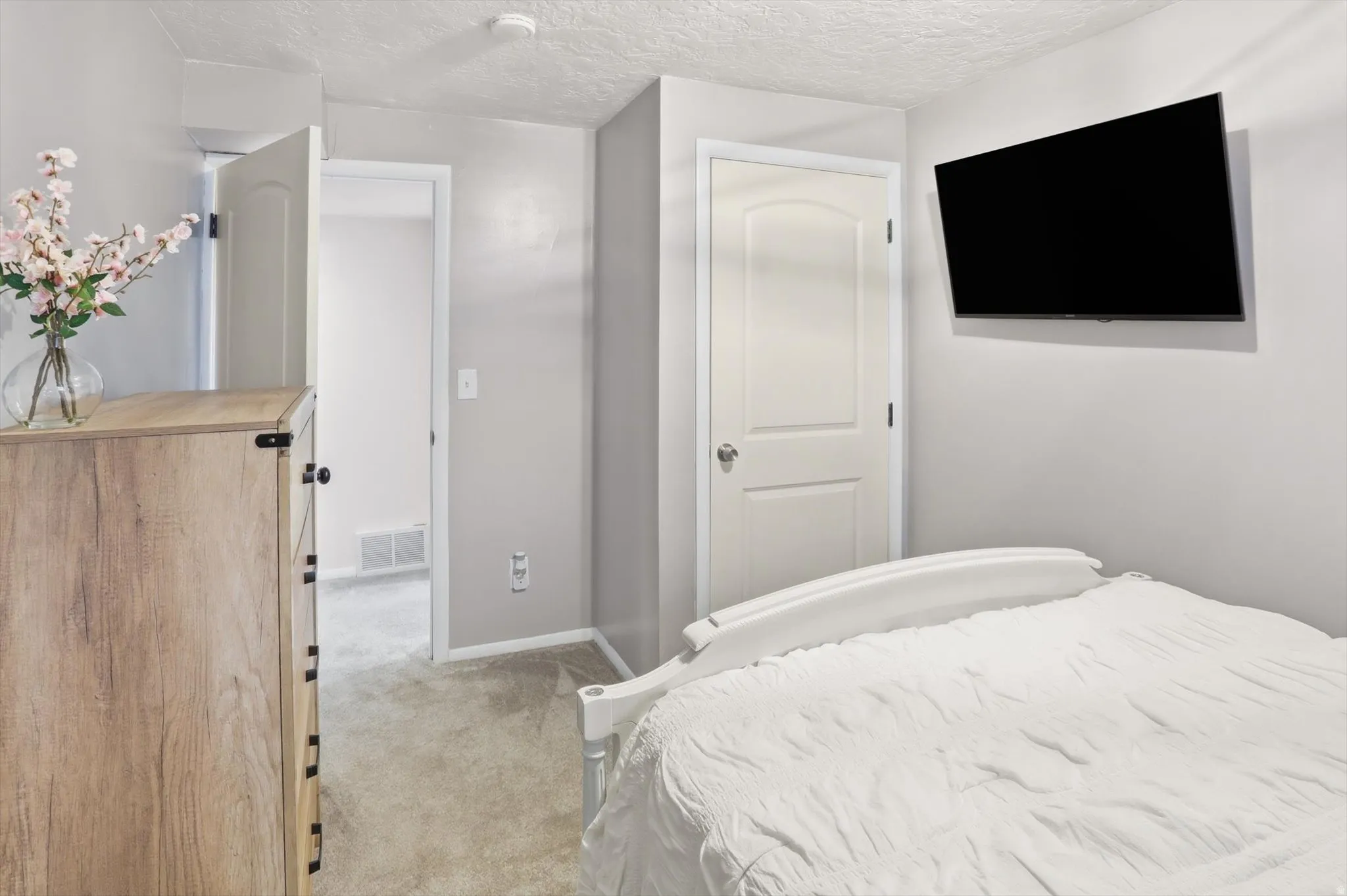 Bedroom featuring light colored carpet and a textured ceiling