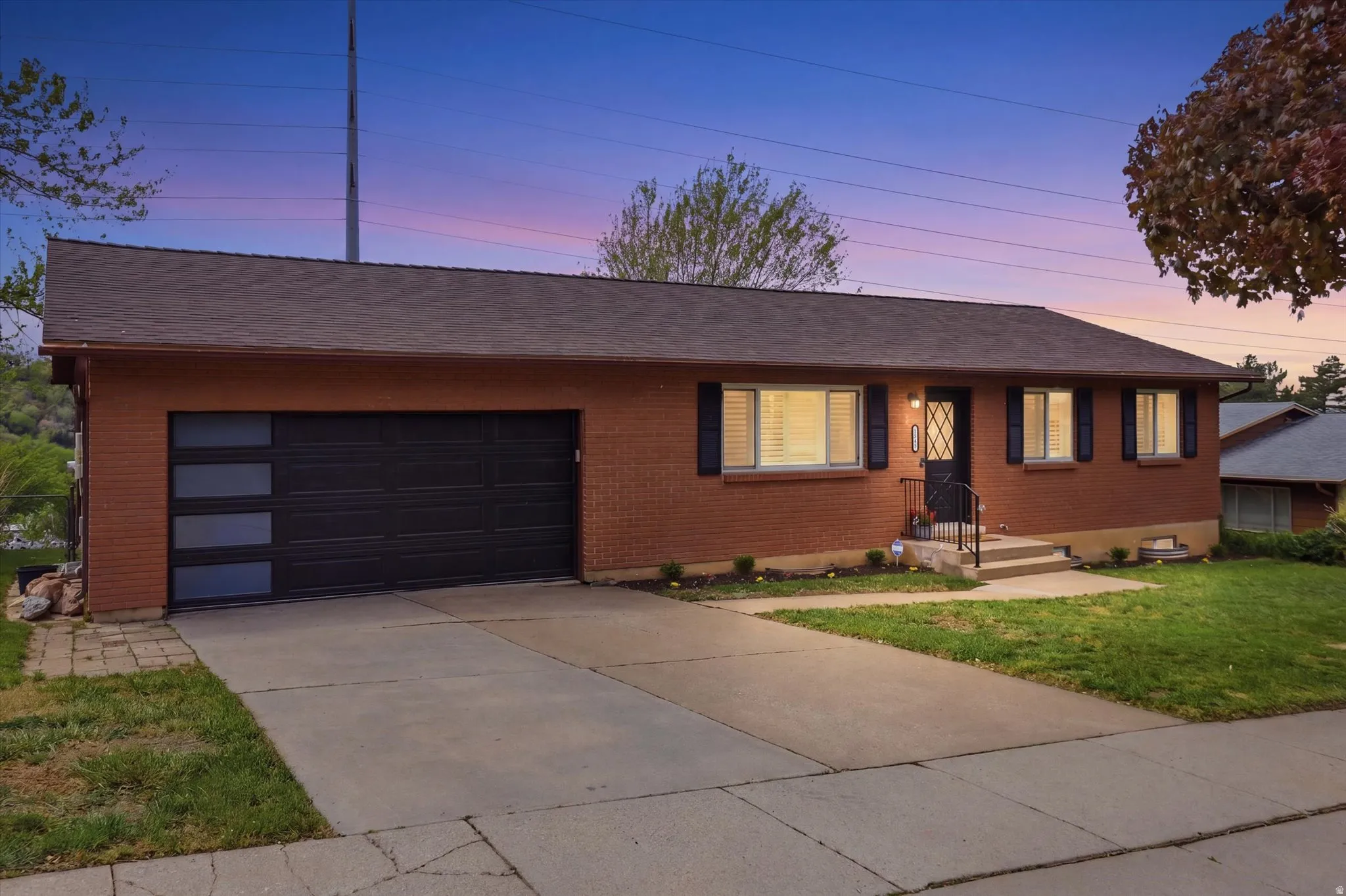 Single story home with a garage, a yard, driveway, roof with shingles, and brick exterior