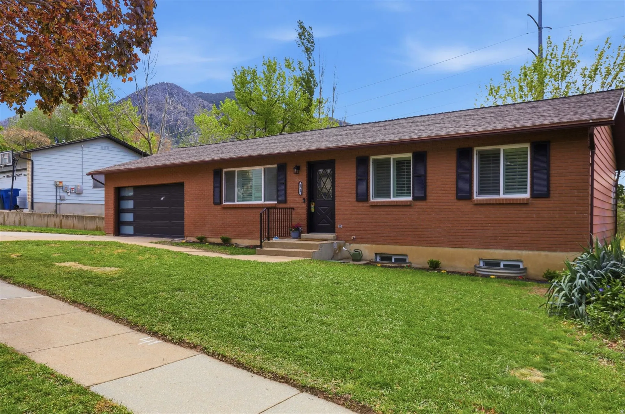 Single story home with brick exterior, a front lawn, concrete driveway, a garage, and a mountain view