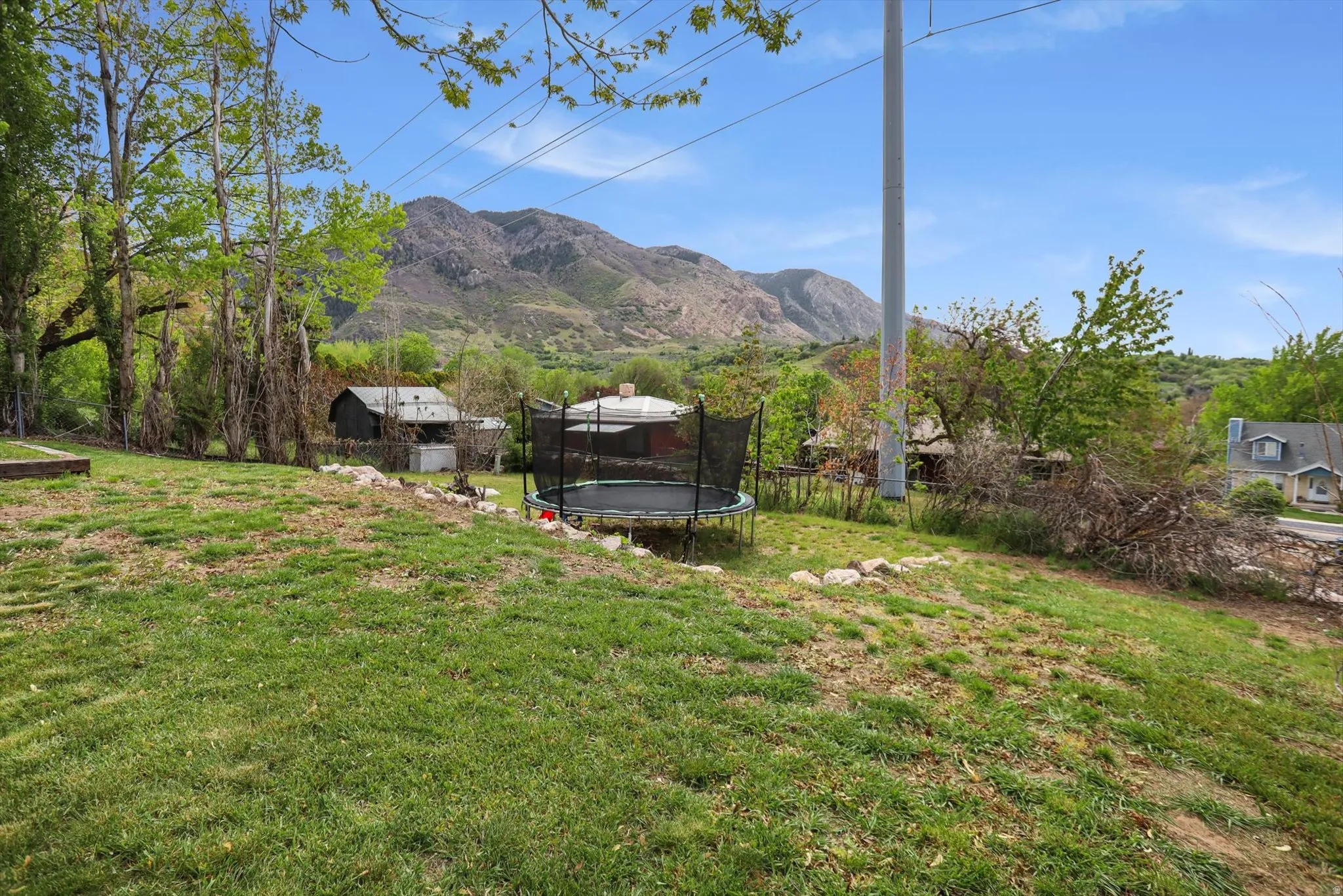 Fenced backyard featuring a trampoline and a mountain view