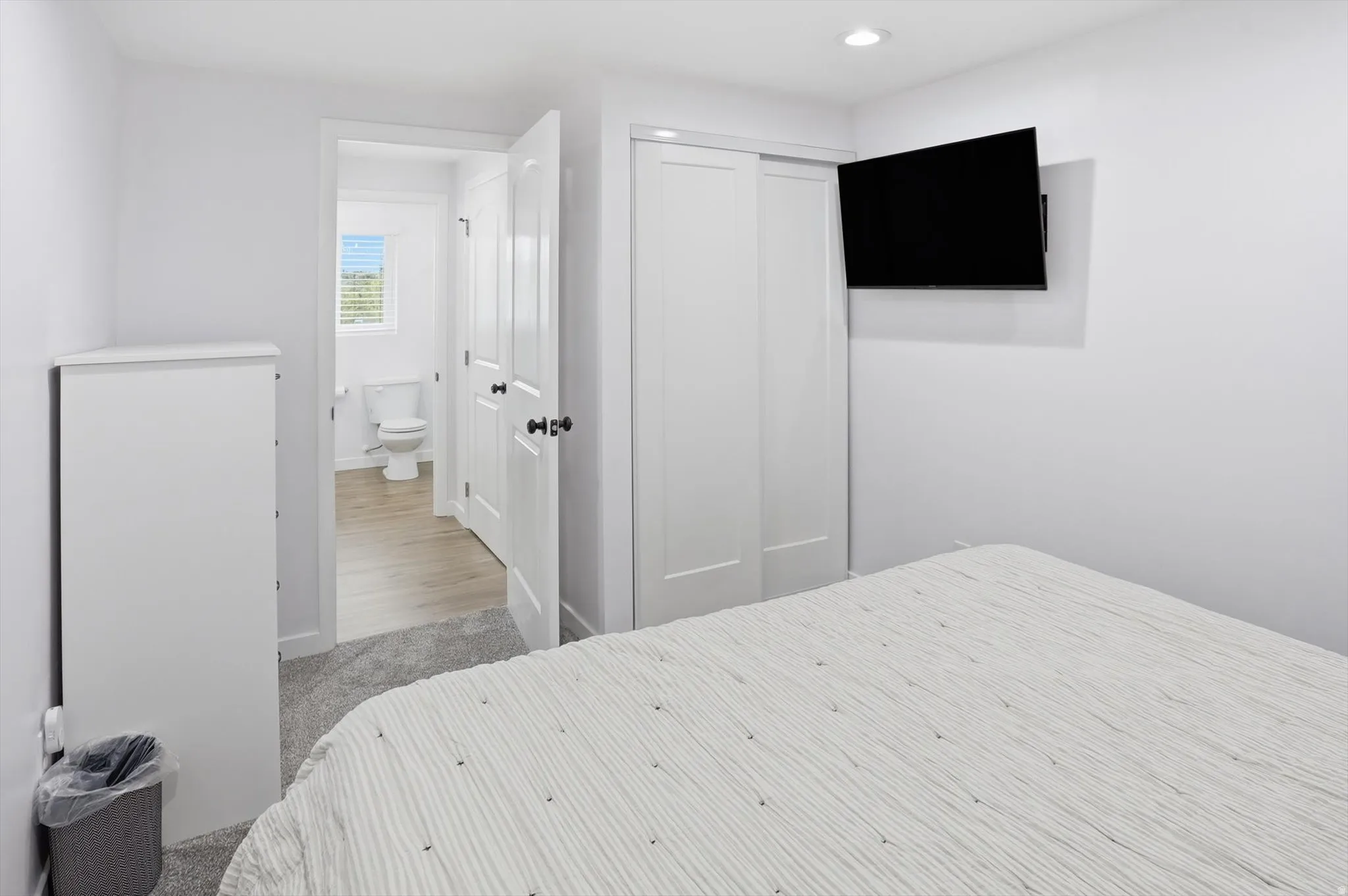 Bedroom with a closet, light colored carpet, and recessed lighting