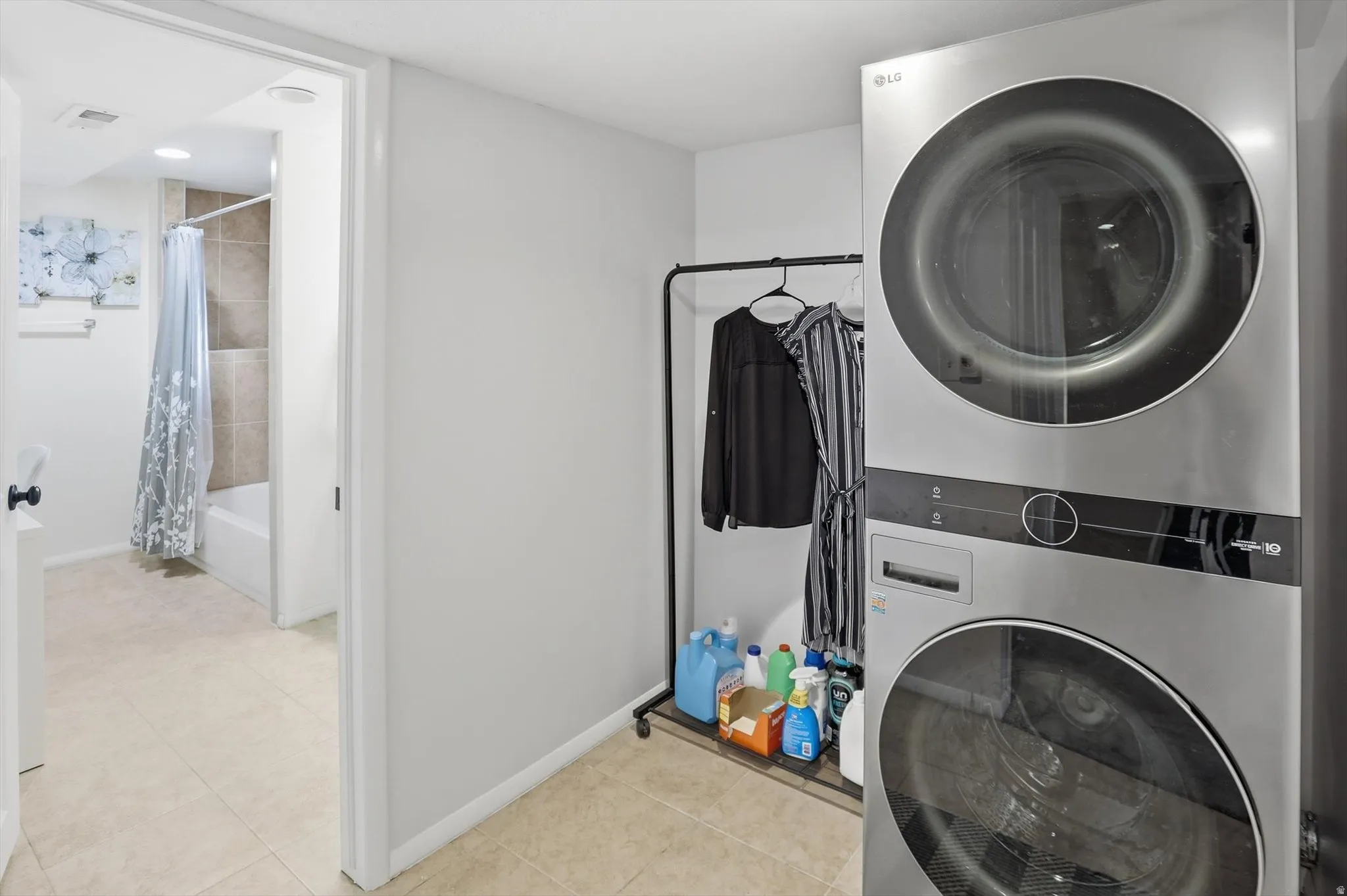 Laundry room featuring stacked washer and dryer and light tile patterned flooring