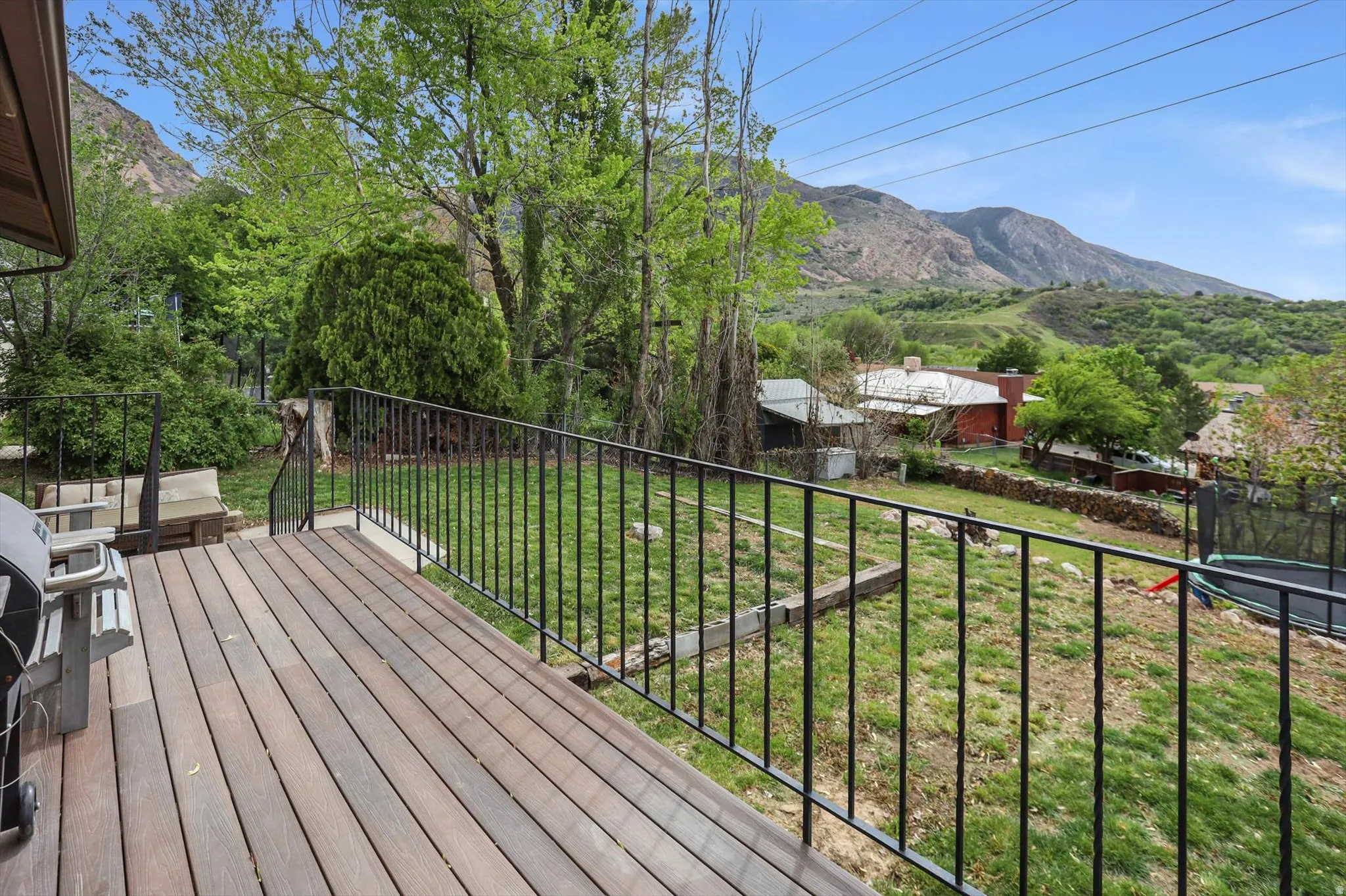 Deck with a trampoline, a lawn, and a mountain view