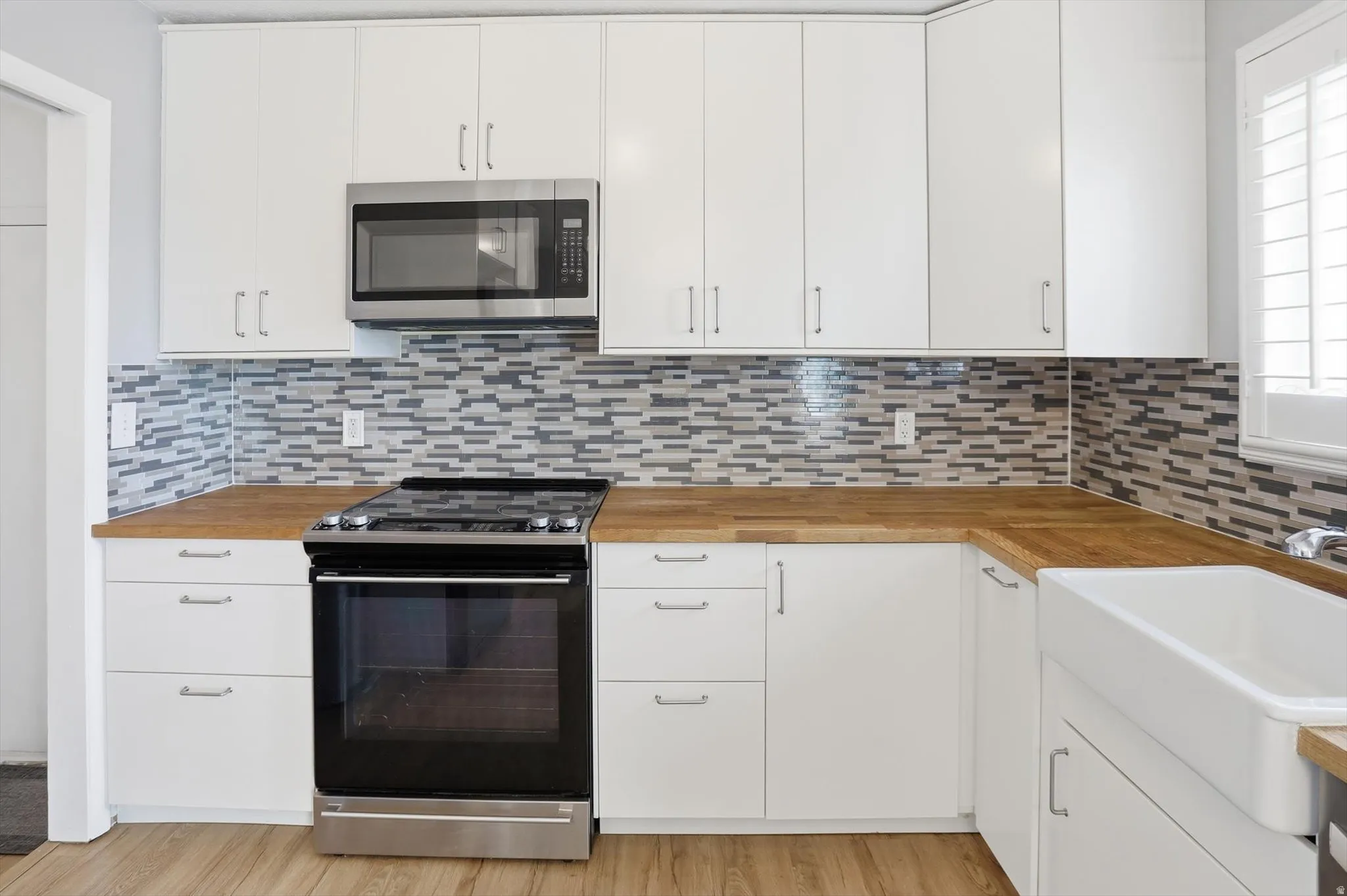 Kitchen featuring wooden counters, slide in range oven, and white cabinetry