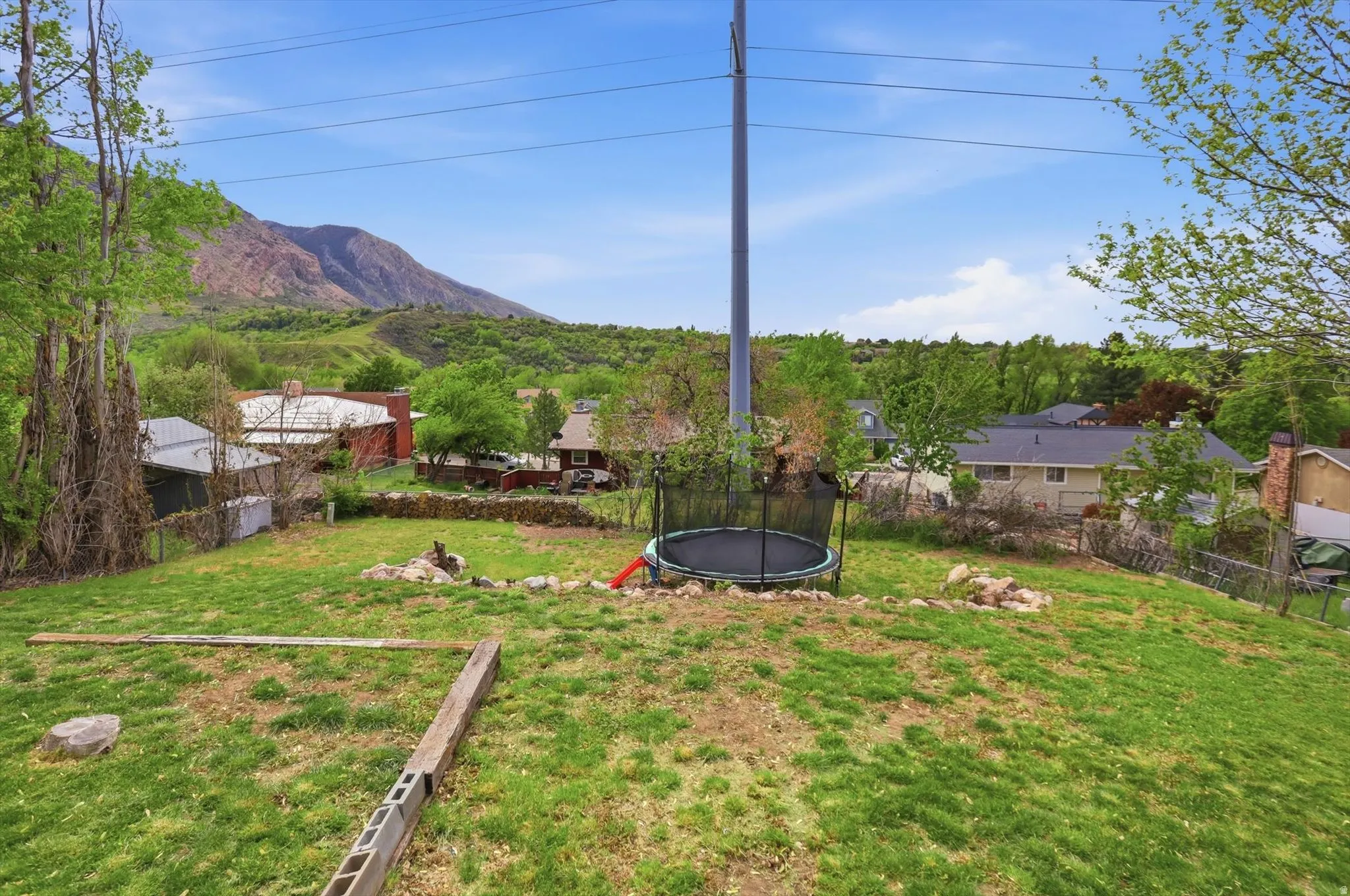 Fenced backyard featuring a trampoline and a mountain view