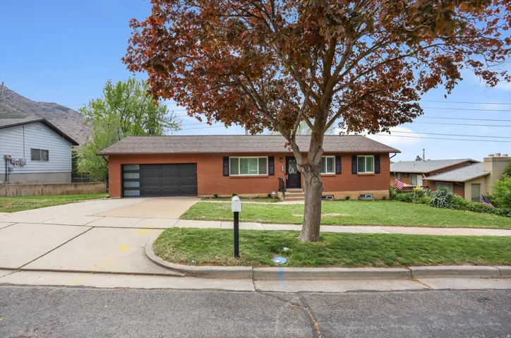 Ranch-style home with brick exterior, driveway, a front yard, and an attached garage