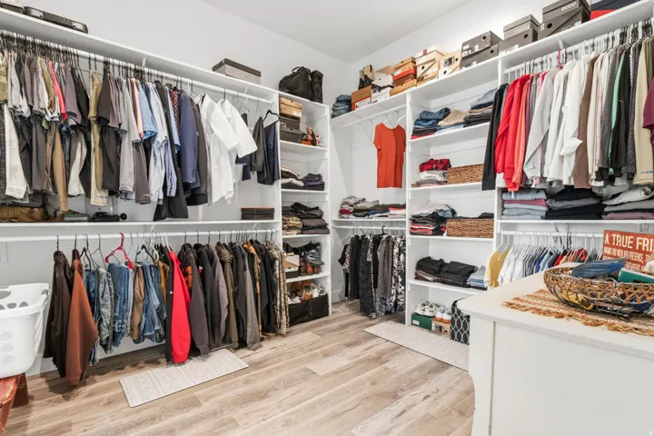 Master bedroom walk in closet with light wood finished floors