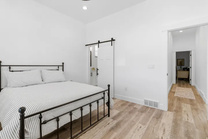 Bedroom with light wood finished floors, connected bathroom, recessed lighting, and a barn door