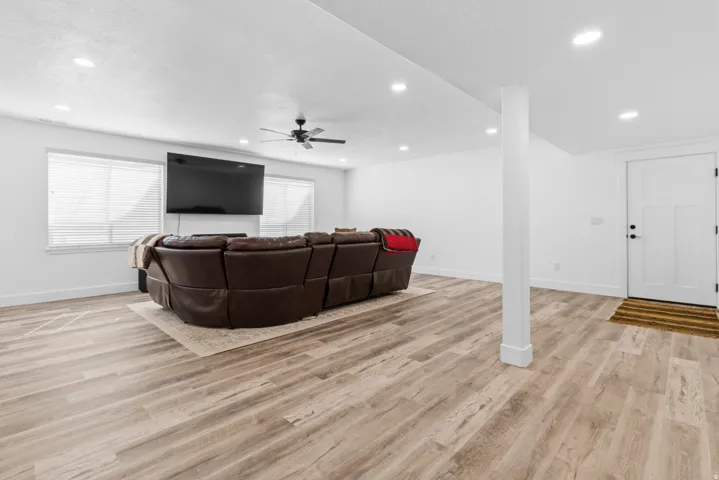 Living room with a ceiling fan, light wood-style flooring, and recessed lighting