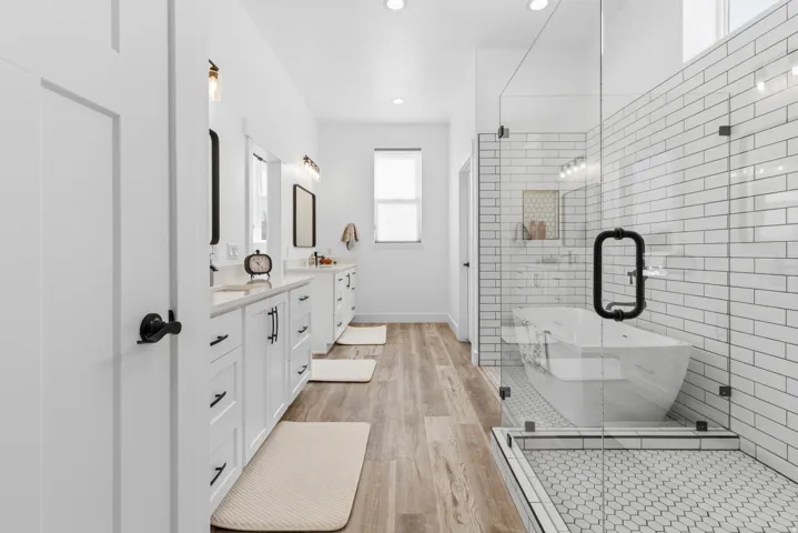 Full bath featuring double vanity, light wood-type flooring, a soaking tub, a shower stall, and recessed lighting