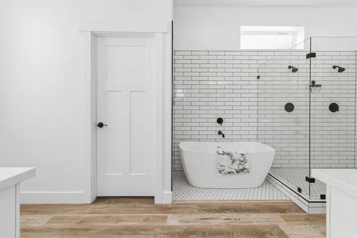 Bathroom featuring vanity, tile walls, a stall shower, a freestanding bath, and light wood finished floors