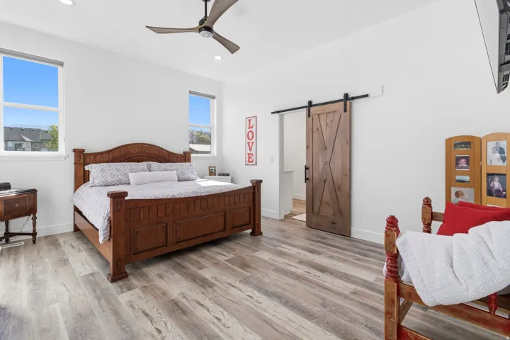 Bedroom with a barn door, recessed lighting, light wood finished floors, and a ceiling fan
