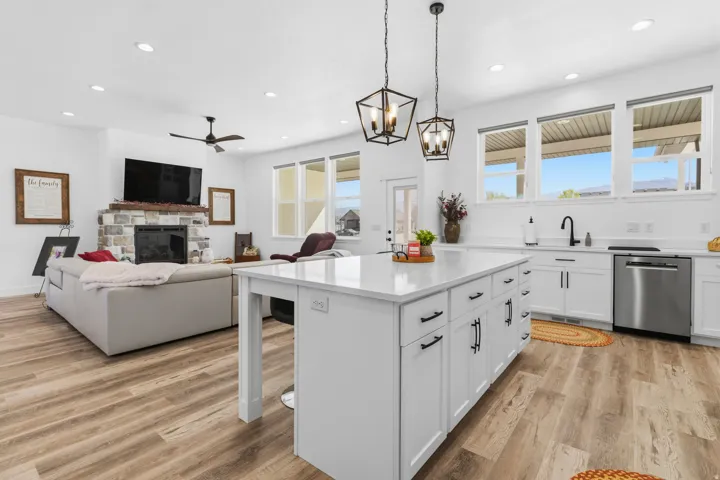 Kitchen featuring a fireplace, a breakfast bar area, light wood-type flooring, and a ceiling fan