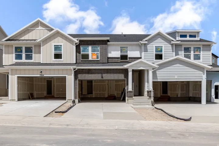 Contemporary townhome exterior featuring varied siding, dark brick accents, a gabled roofline, and attached garages