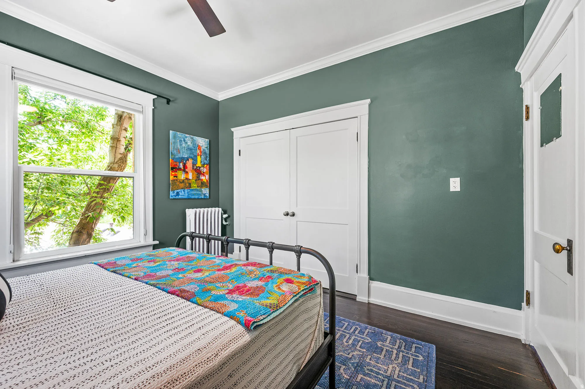 Bedroom with ornamental molding, dark wood finished floors, a closet, radiator heating unit, and ceiling fan
