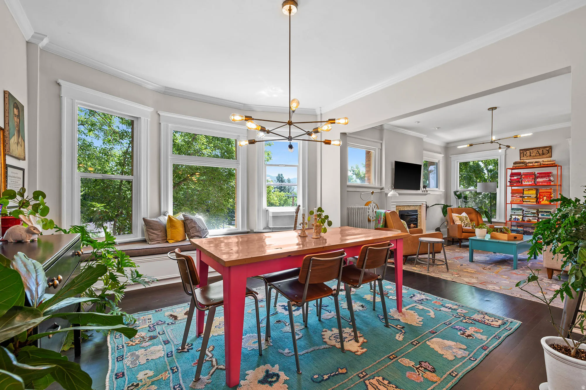 Dining space featuring suspended lighting, ornamental molding, dark wood-type flooring, and a glass covered fireplace