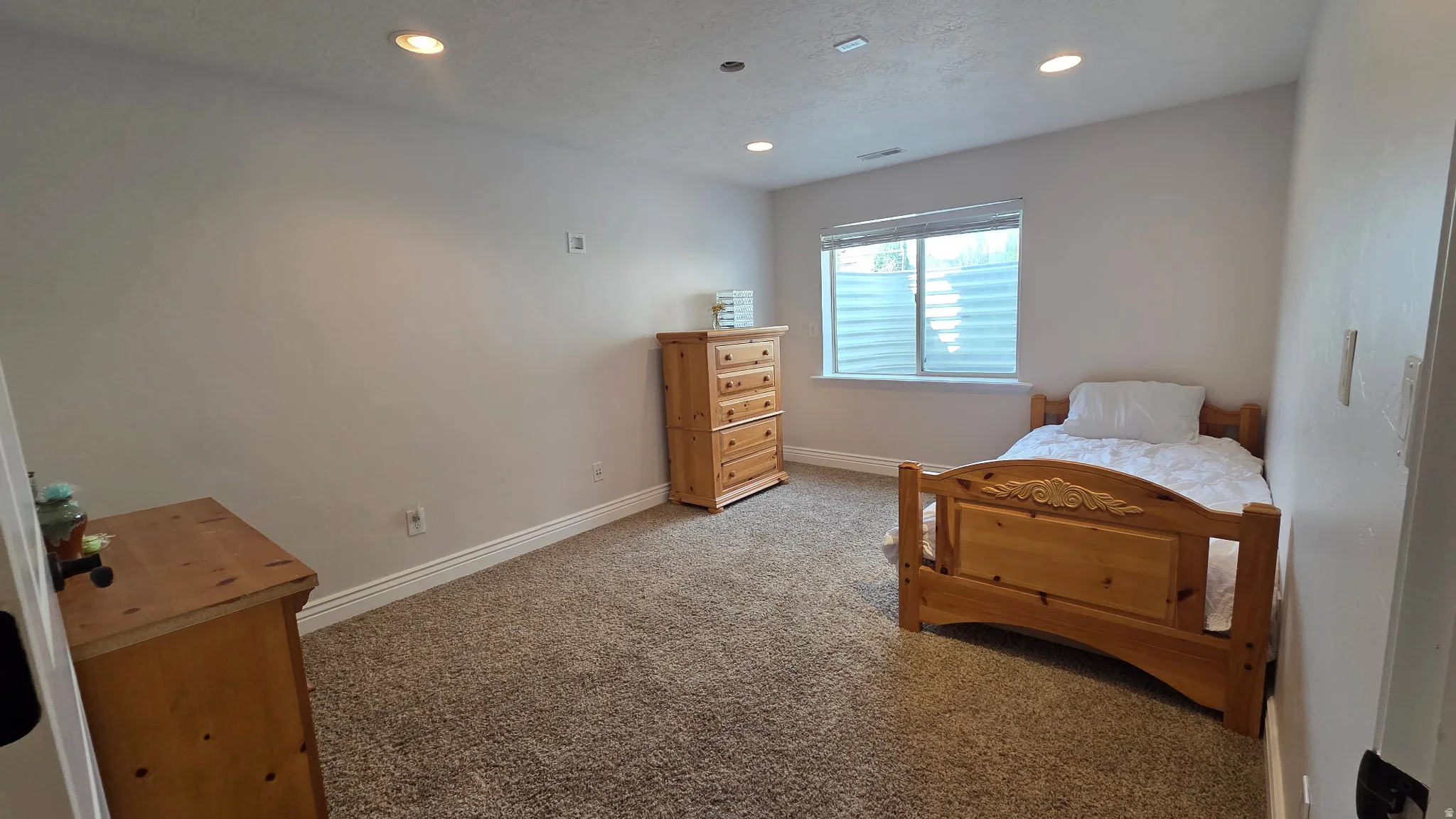 Room with light colored carpet and recessed lighting