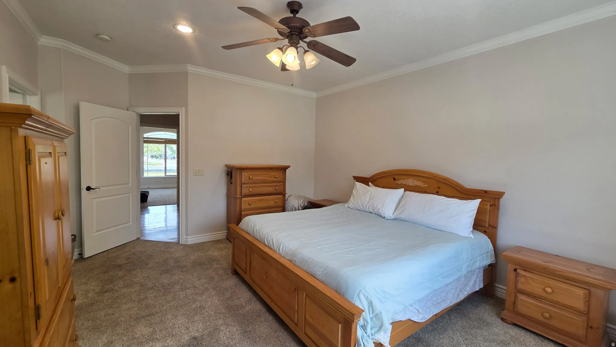 Primary Bedroom featuring dark colored carpet, ornamental molding, and ceiling fan
