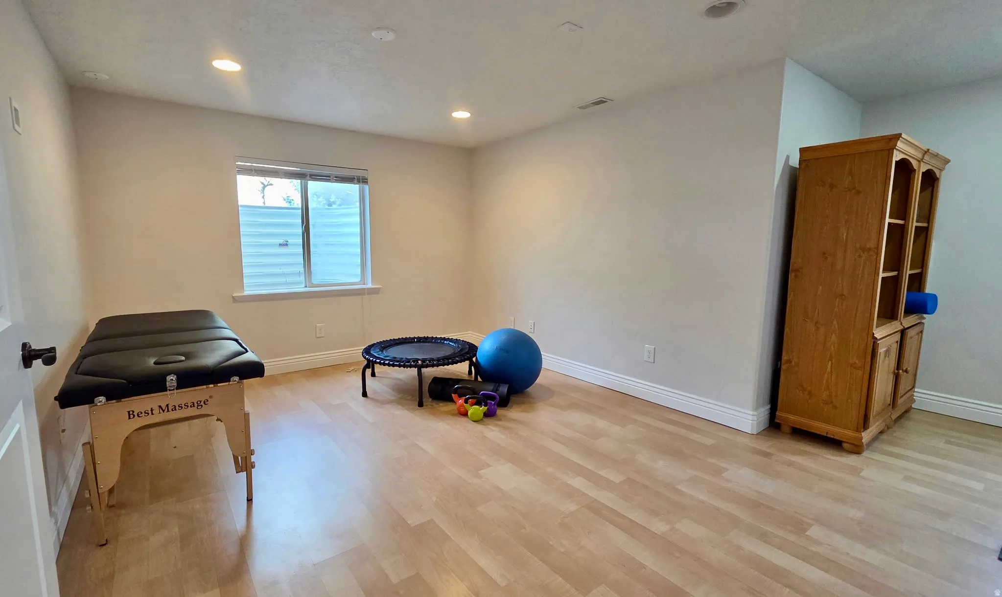 Exercise room with recessed lighting and light wood-style flooring