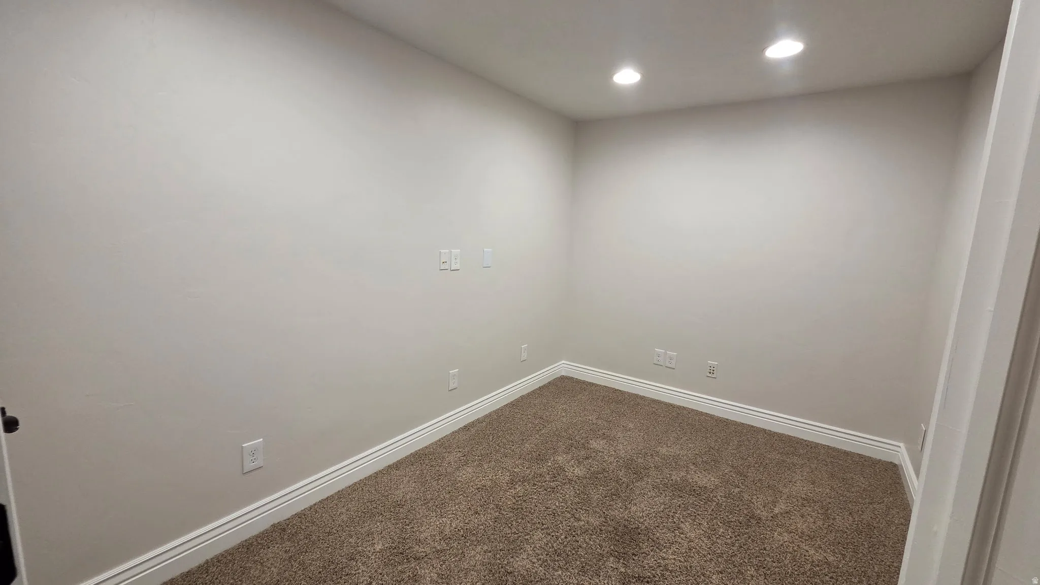 Empty room with dark colored carpet and recessed lighting