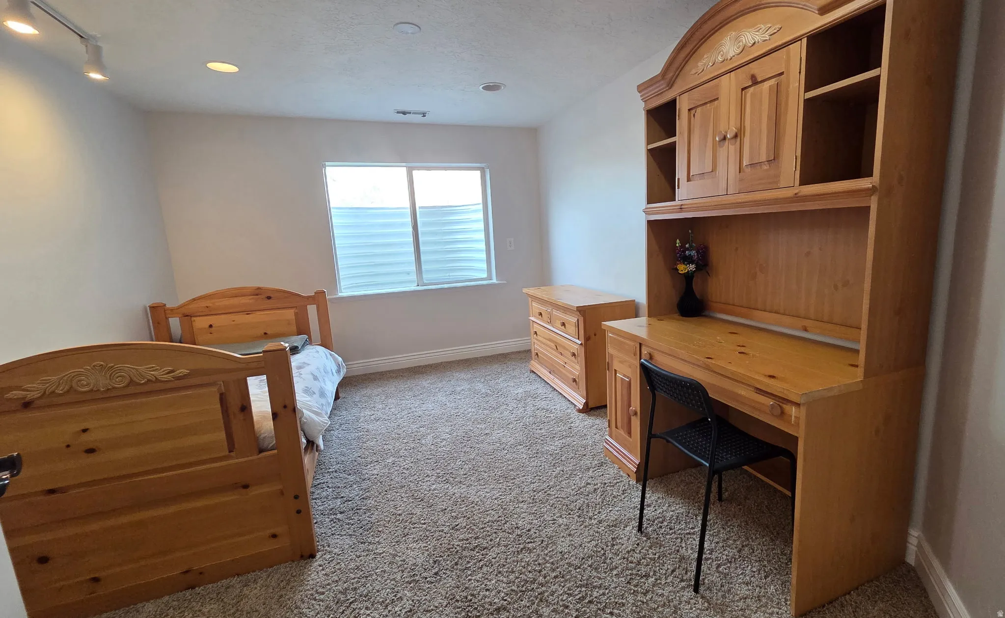 Room featuring light carpet, track lighting, a textured ceiling, and a desk