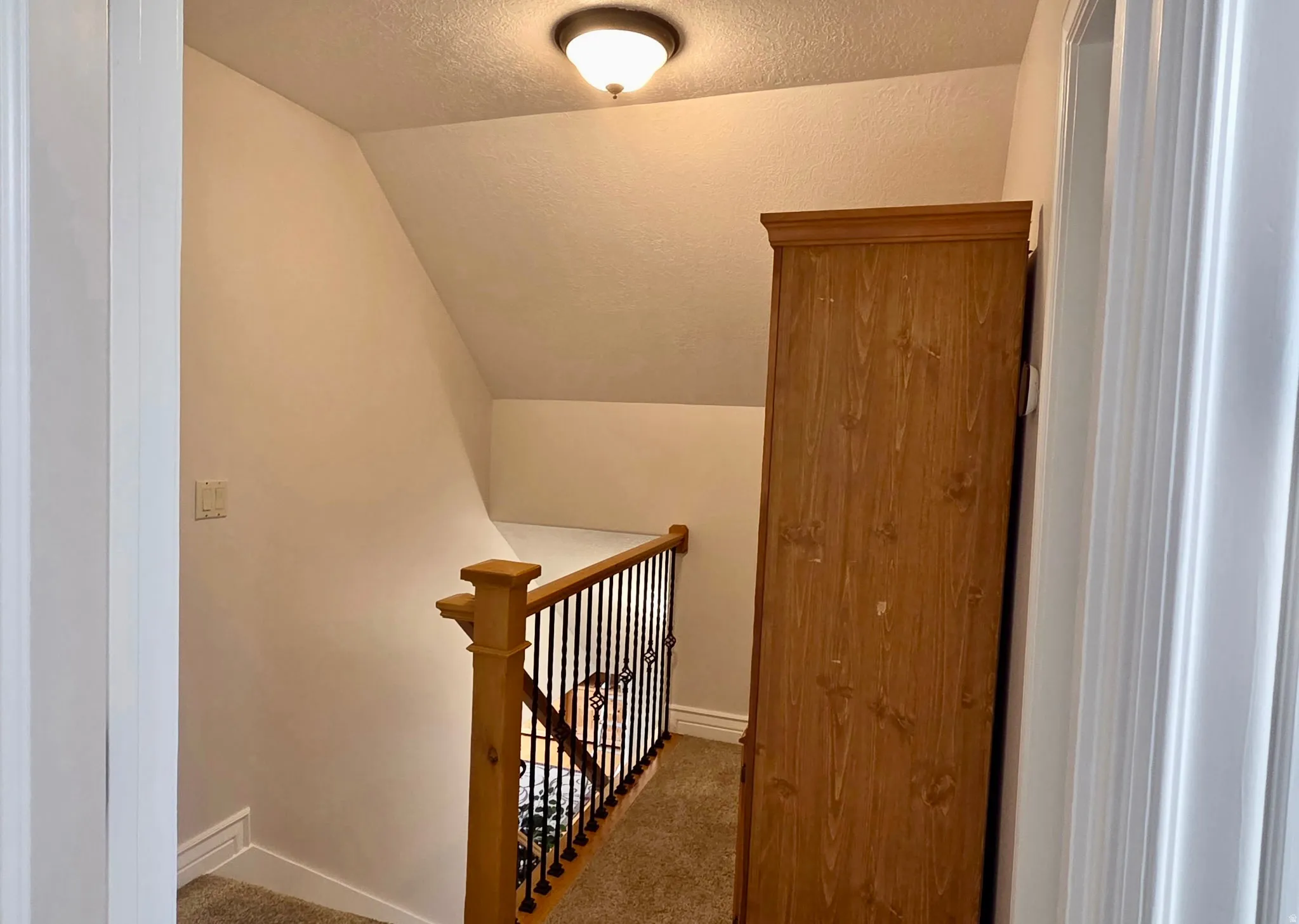 Stairway with a textured ceiling and carpet flooring