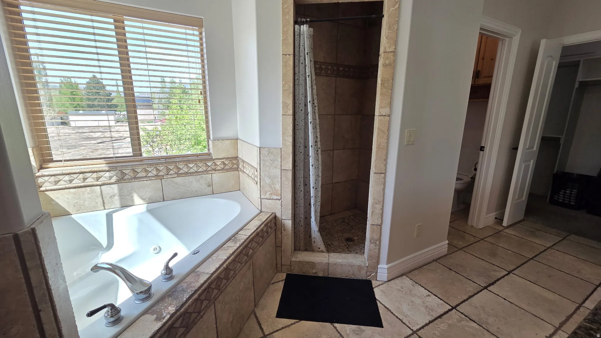 Primary bath with a stall shower, a whirlpool tub, and travertine tile patterned floors