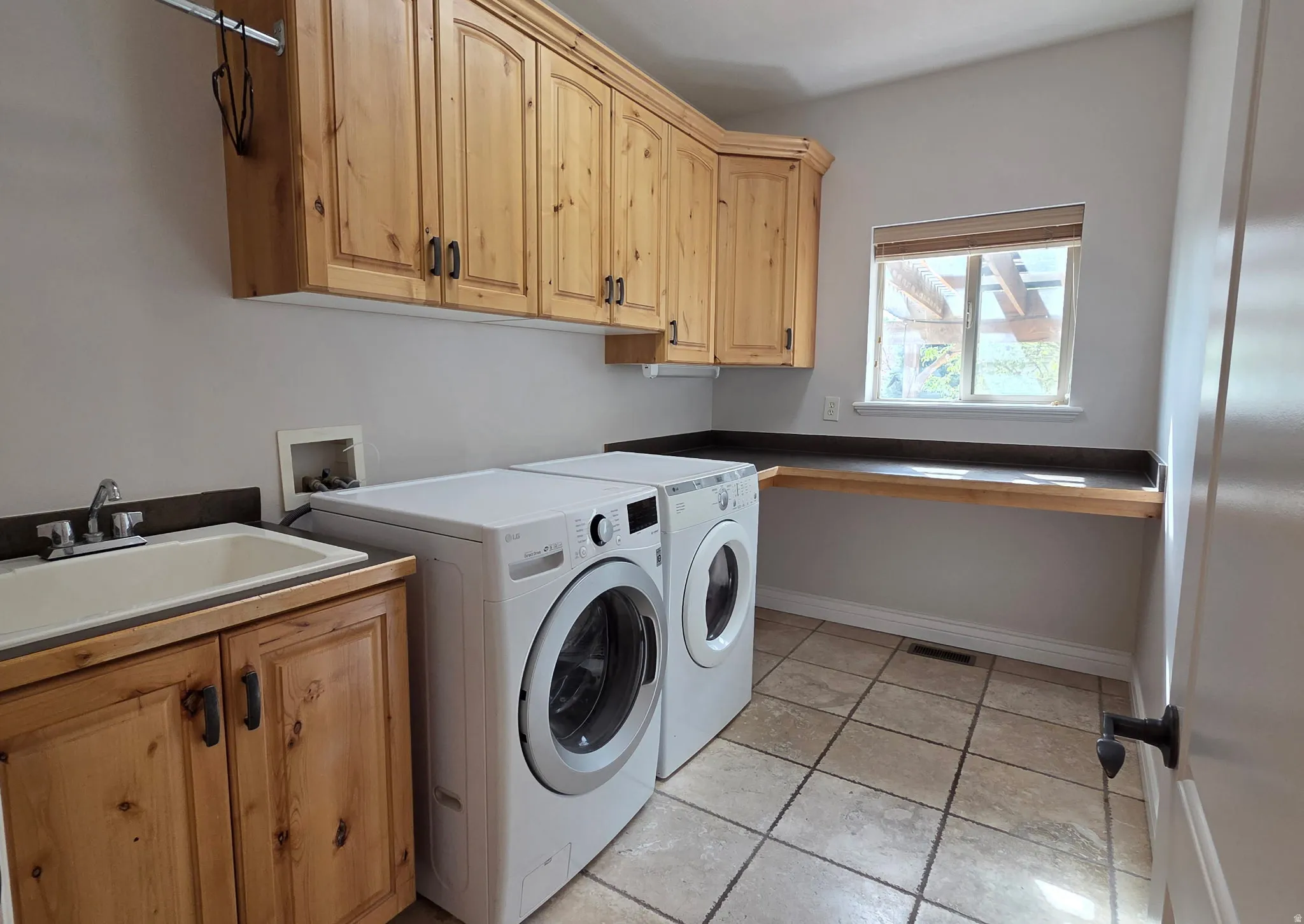 Laundry room with light tile patterned floors, washing machine and clothes dryer, and cabinet space