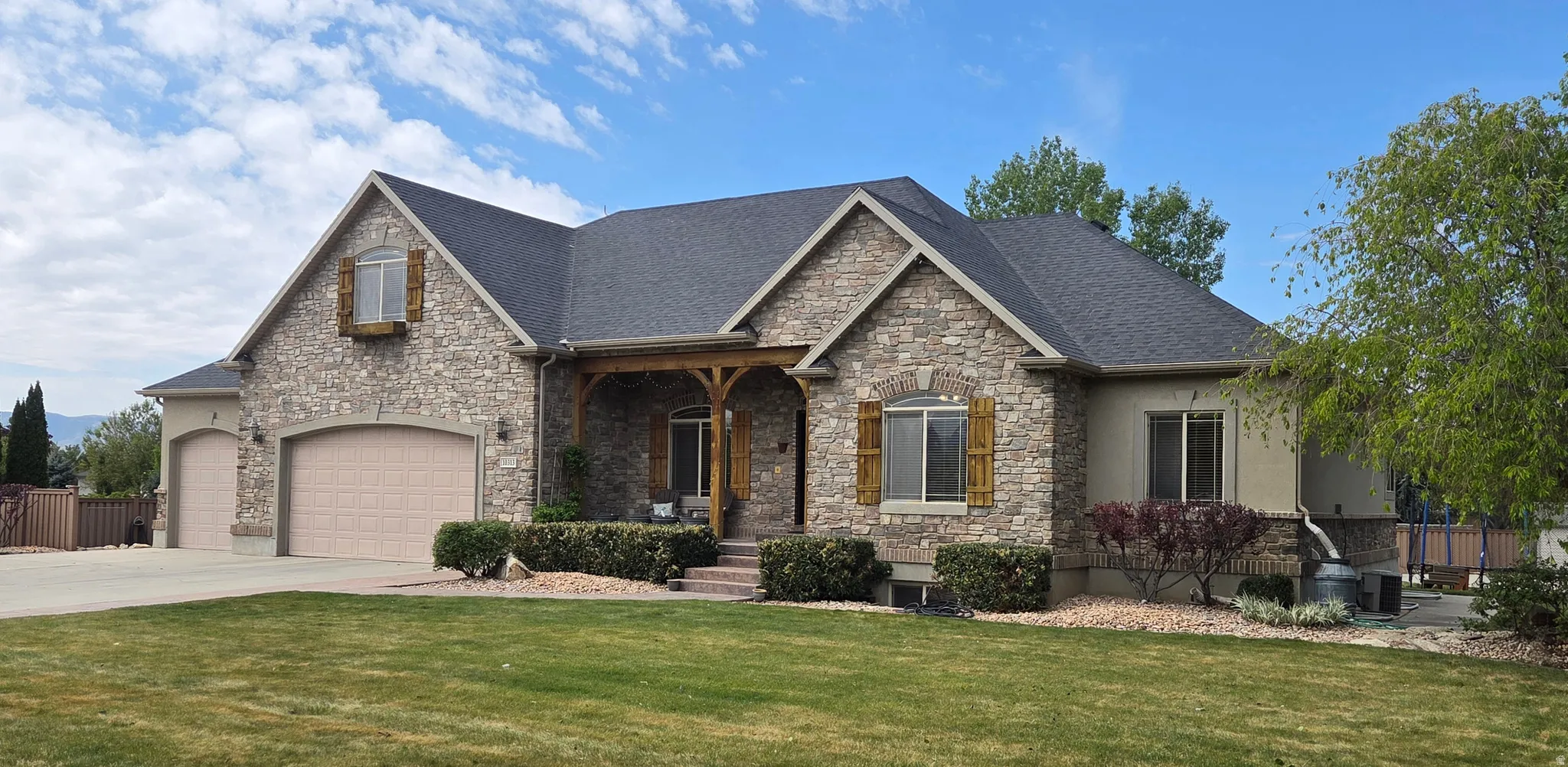 Craftsman-style home with stone siding, covered porch, concrete driveway, a shingled roof, and a garage