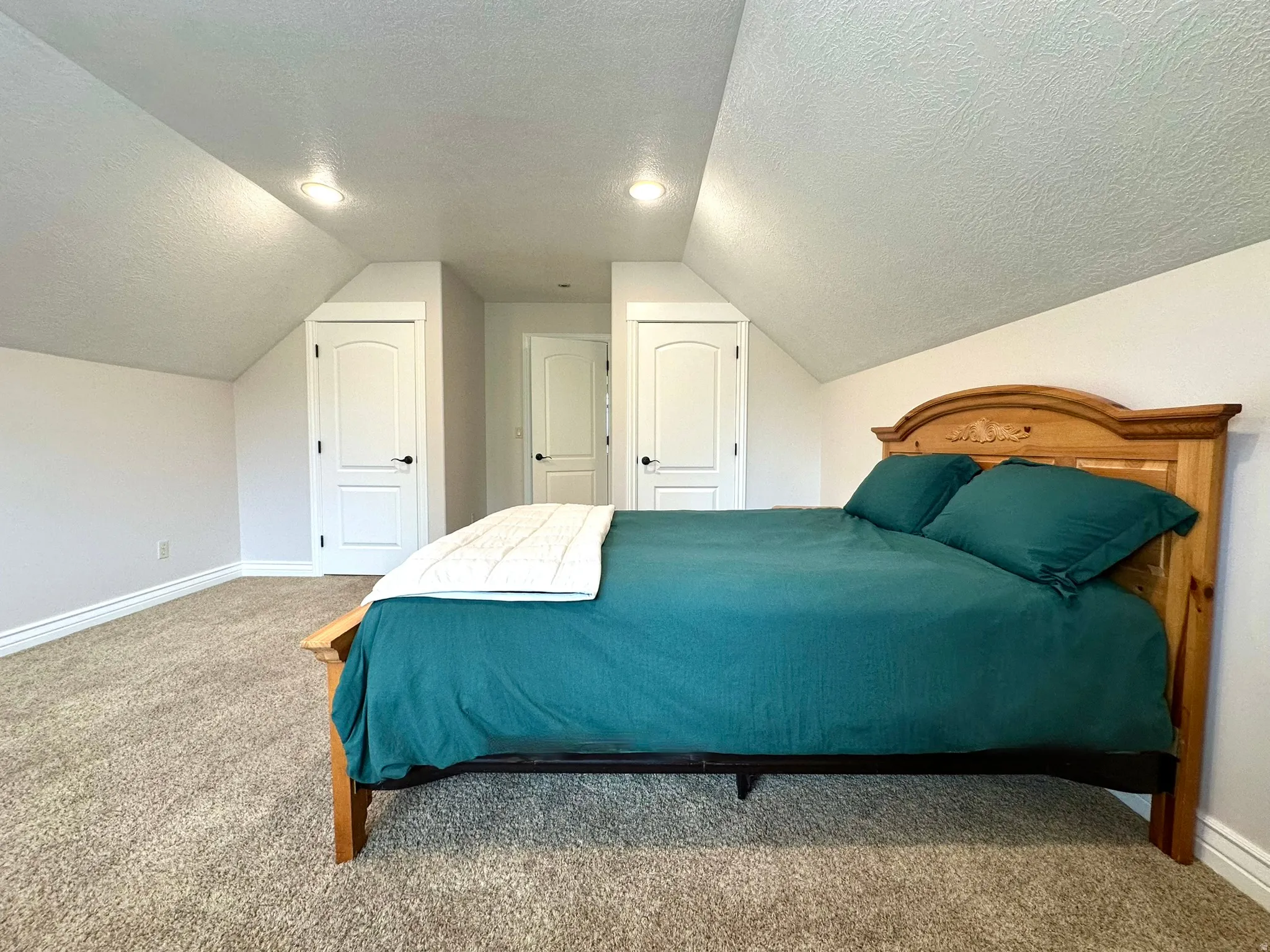 Carpeted room featuring sloped ceilings, recessed lighting, white trim, and dual walk-in closets.