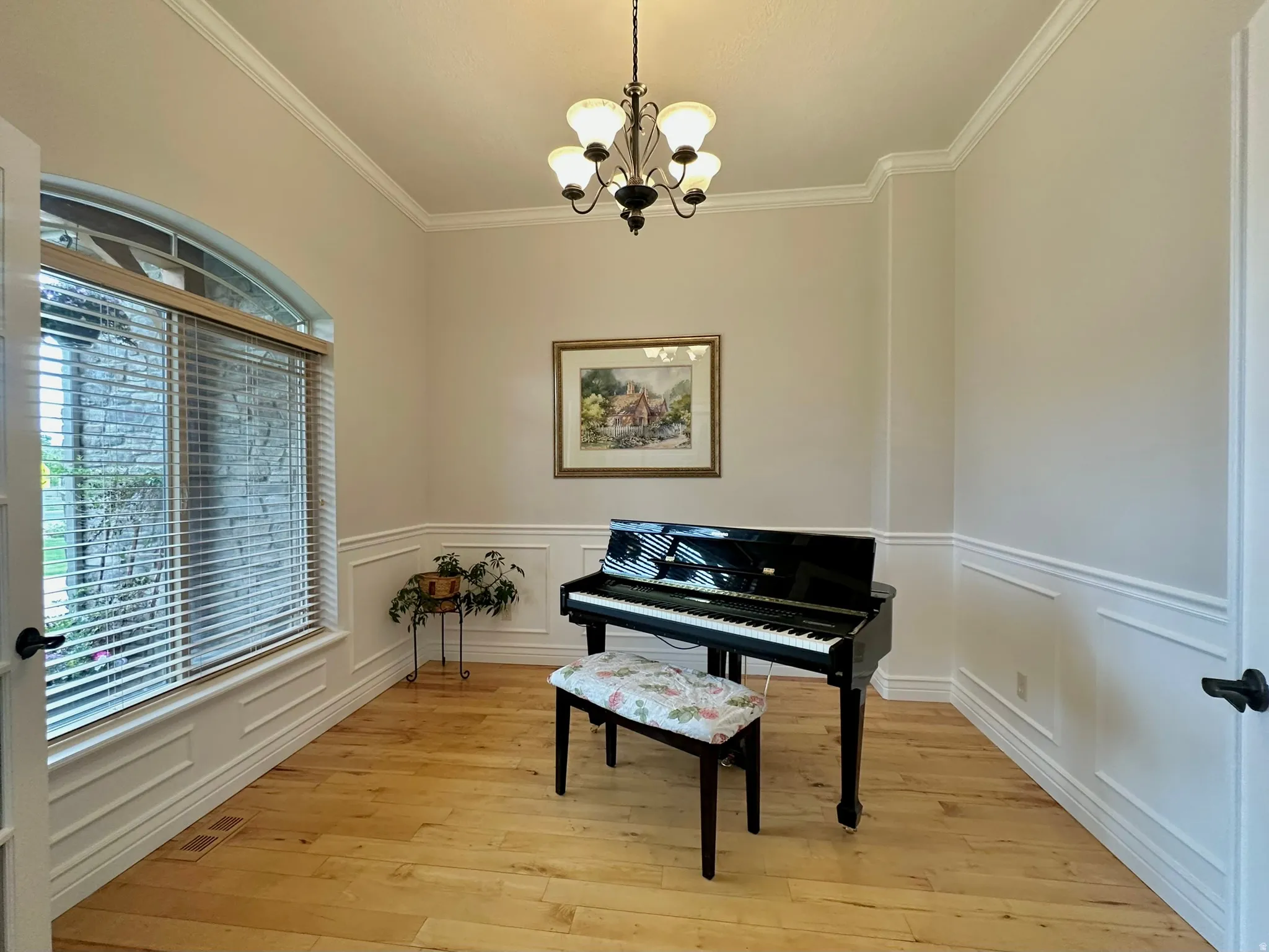 Hardwood flooring with white wainscoting and crown molding and french doors.