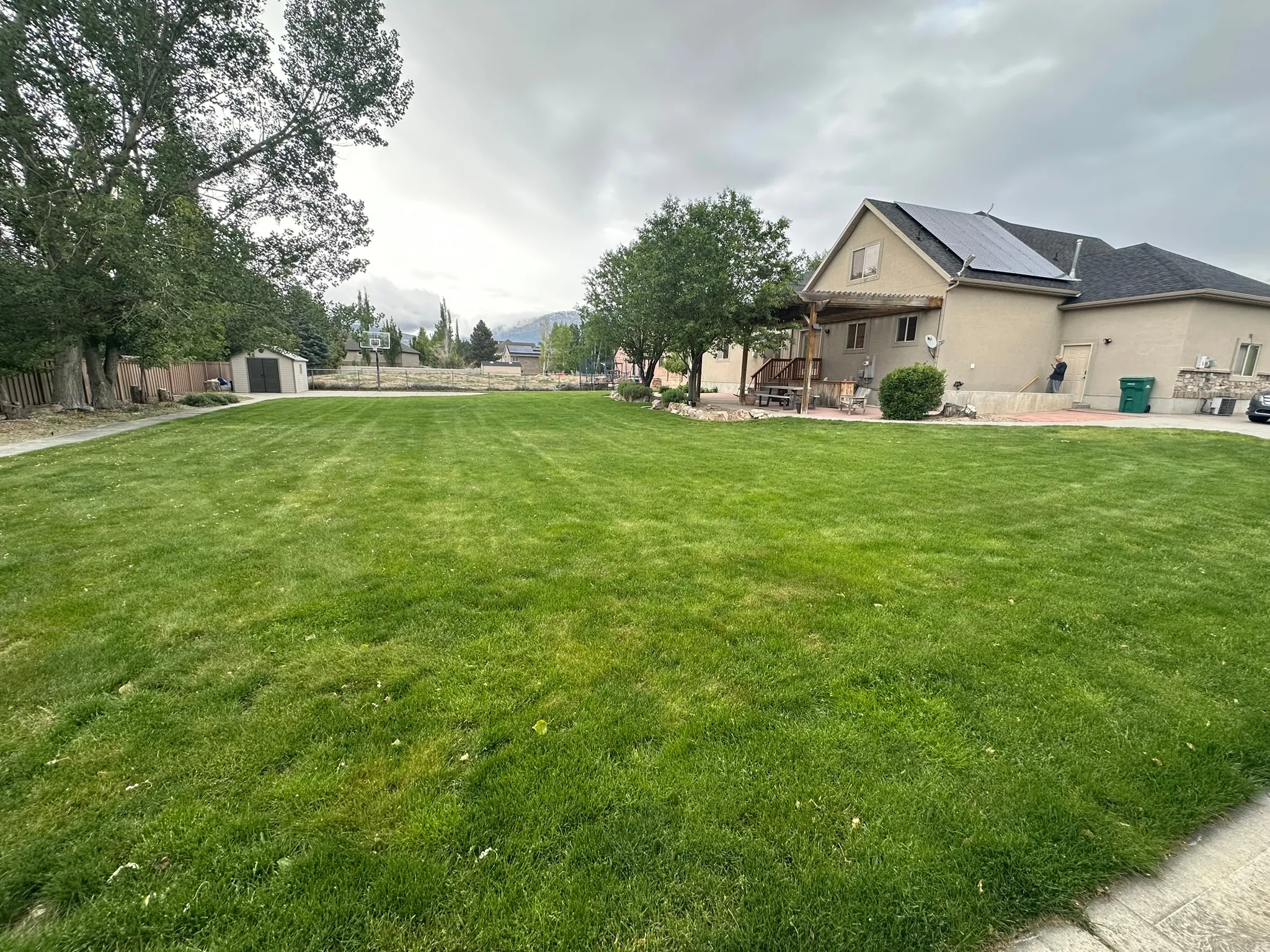 .71 Acre includes expansive grassy yard with mature trees, covered patio and sport court.