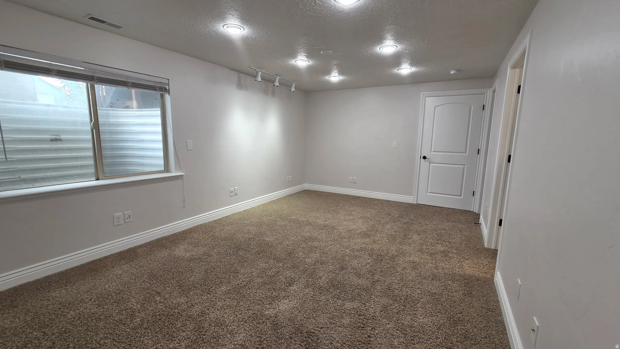 Bedroom room, with recessed lights, light colored carpet, rail lighting and large walk-in closet.
