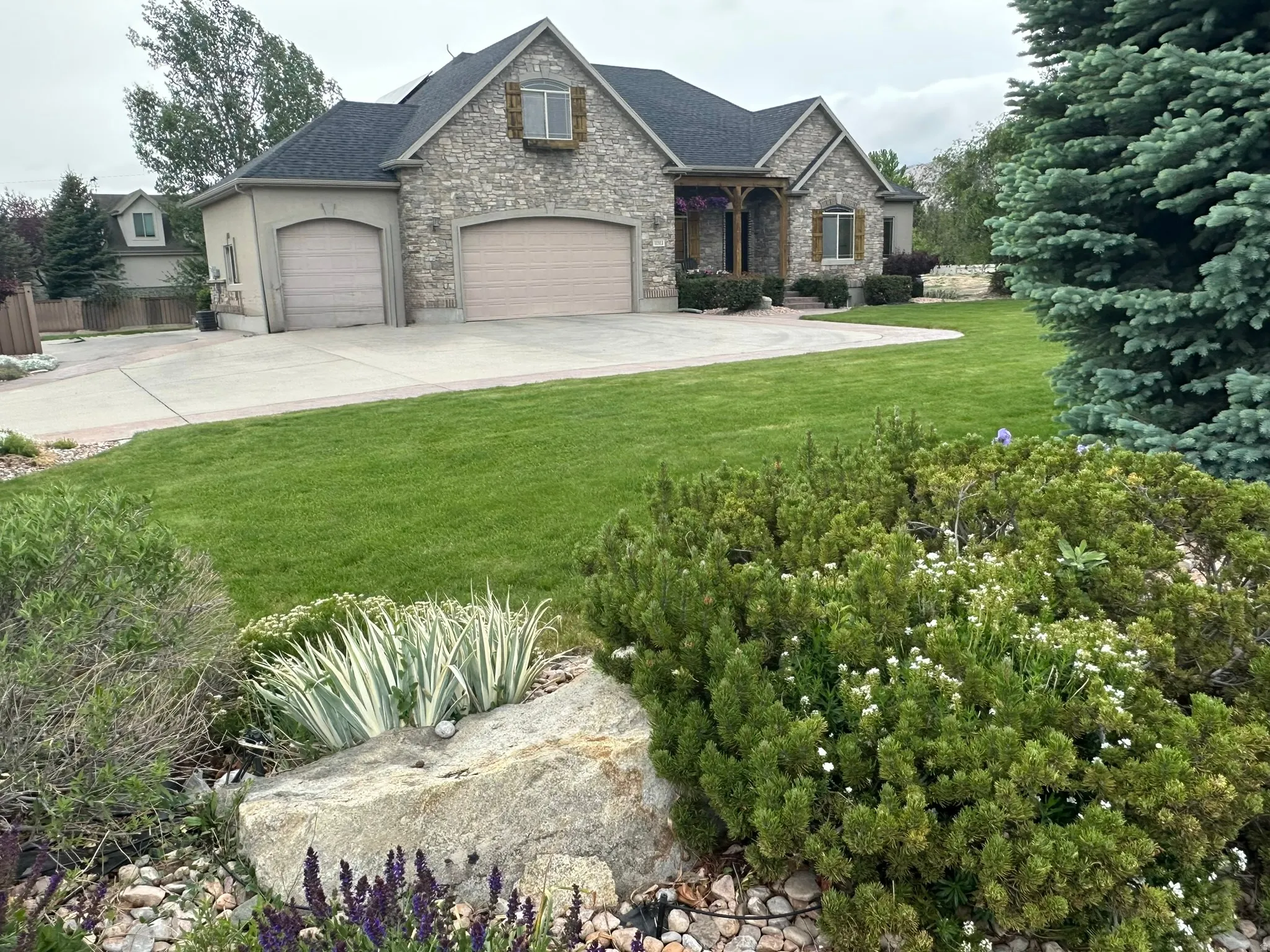 Stone and stucco exterior featuring a multi-gable roofline, wood accents, beautifully landscaped.