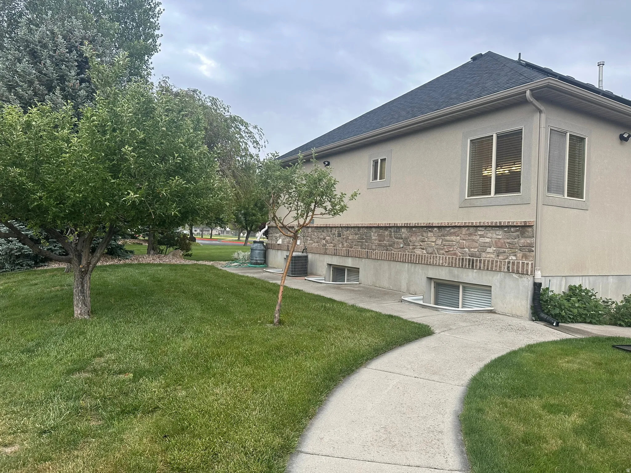 Exterior stucco finish with stone facade detailing, with wrap around concrete sidewalks.