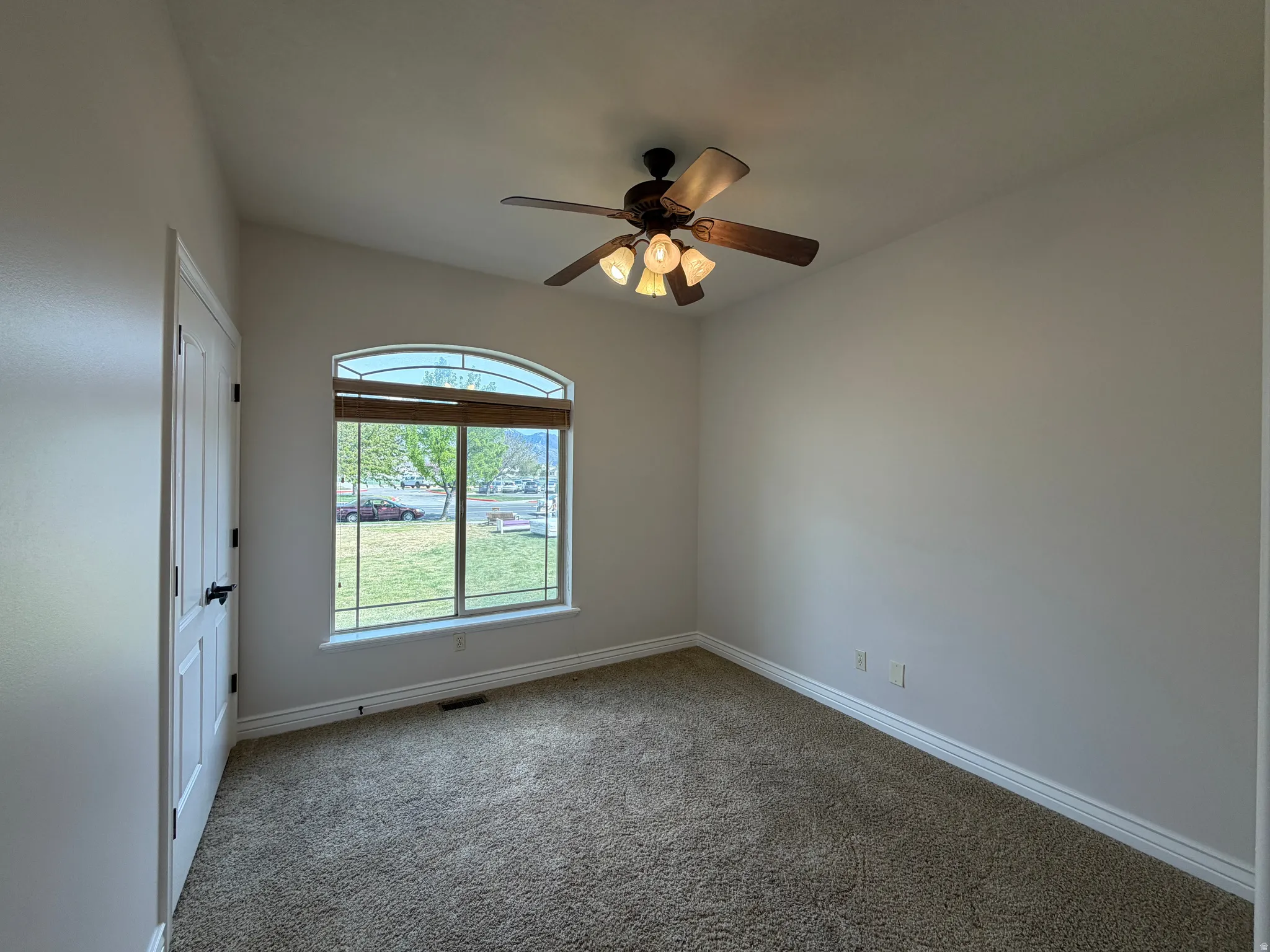 Bedroom room with light colored carpet and a ceiling fan