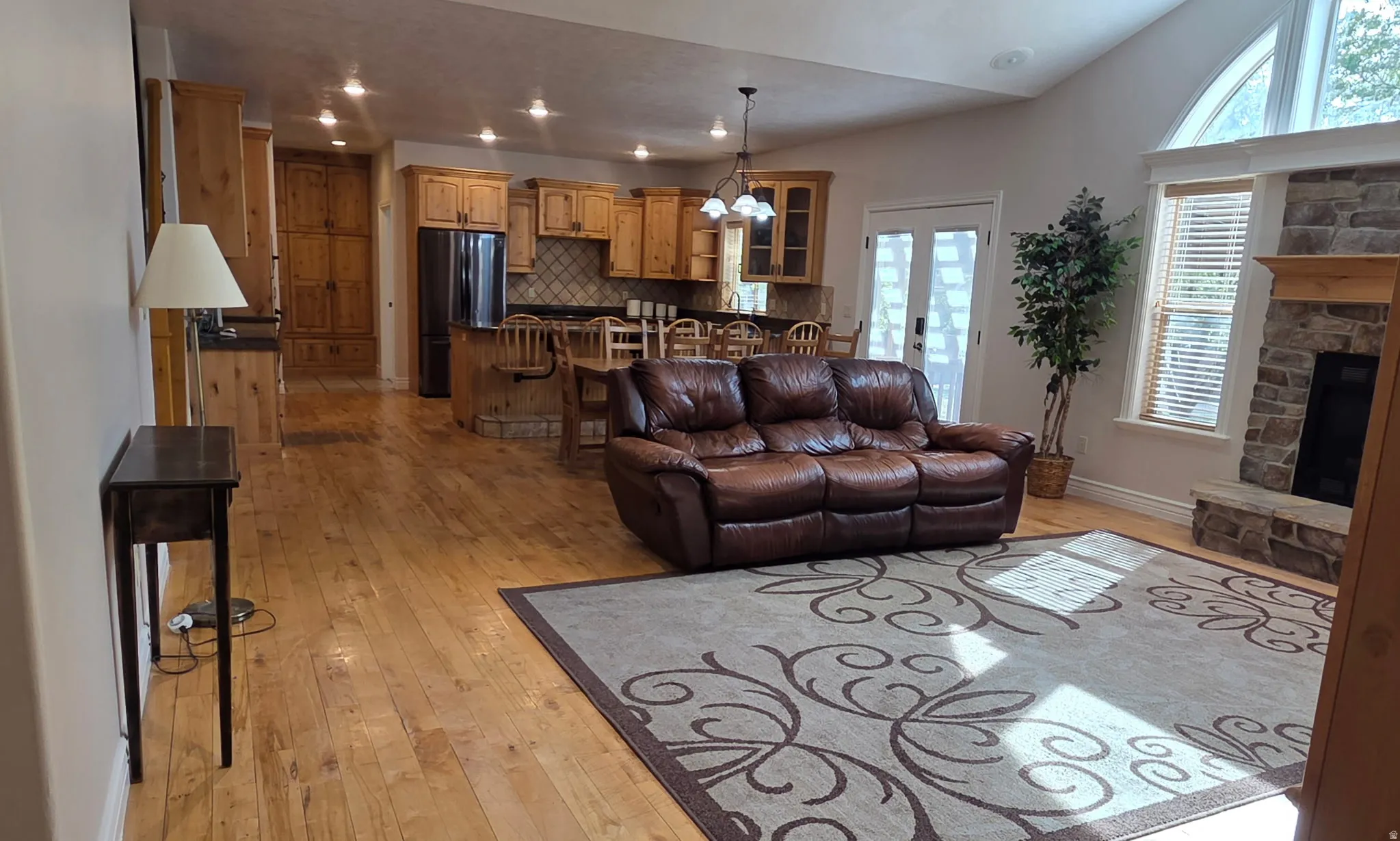 Living area with light wood finished floors, hanging lights, a fireplace, and french doors