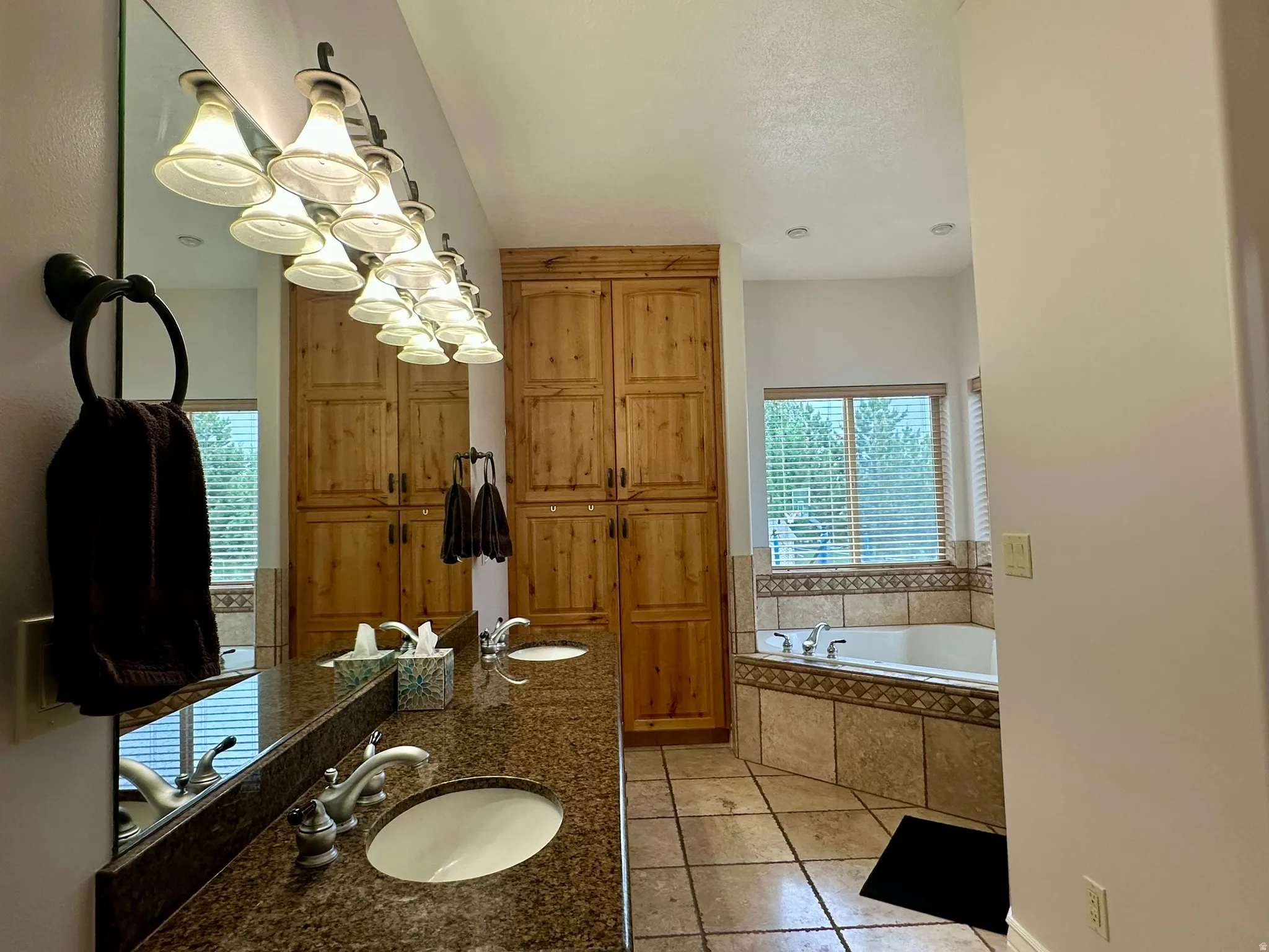 Bathroom featuring a double vanity with granite-style countertops, dual undermount sinks, and a full-width mirror