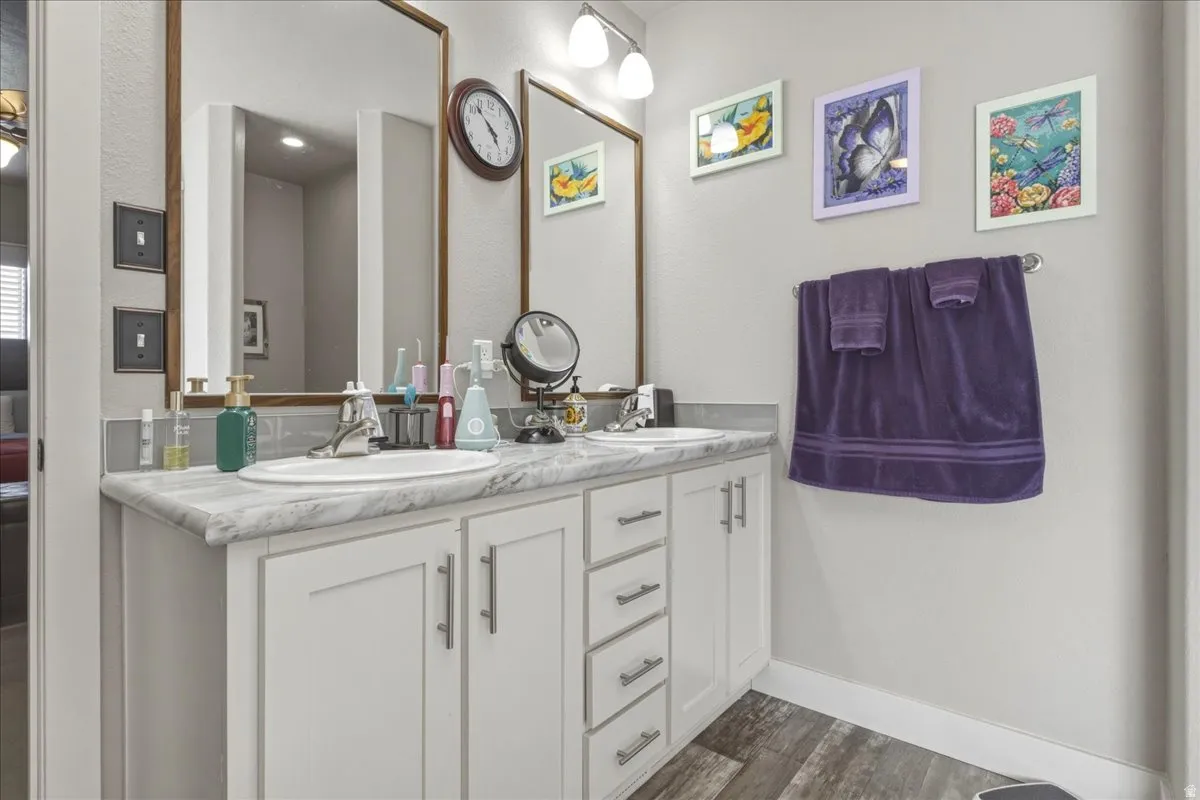 Full bathroom with double vanity and dark wood finished floors