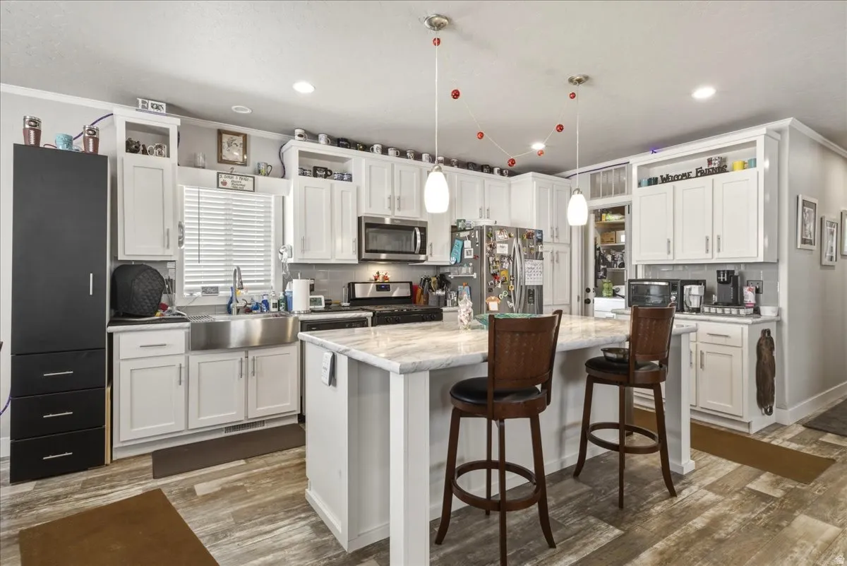 Kitchen featuring stainless steel appliances, white cabinetry, tasteful backsplash, a kitchen bar, and a kitchen island