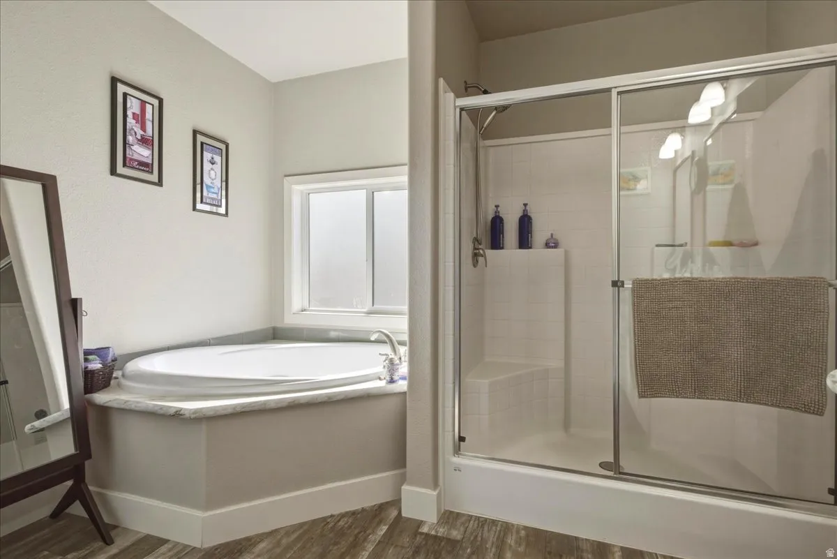 Bathroom with a stall shower, a garden tub, and dark wood finished floors