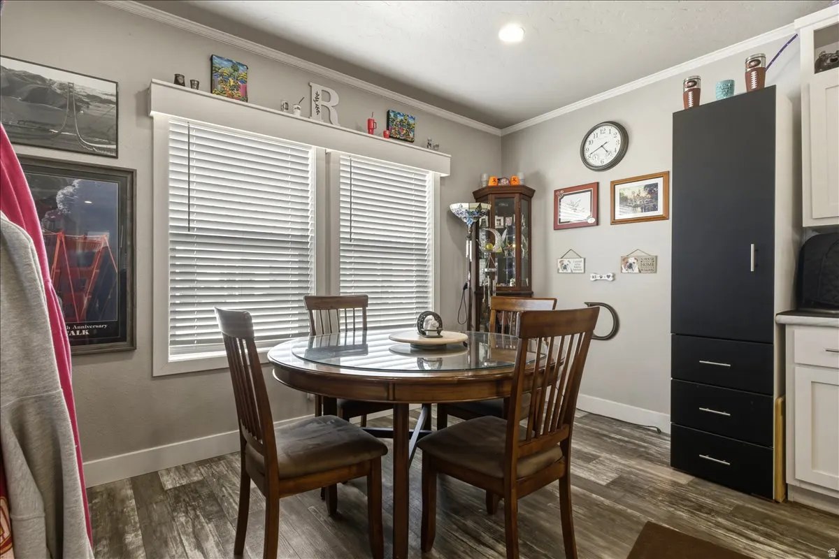 Dining space with dark wood-type flooring and crown molding